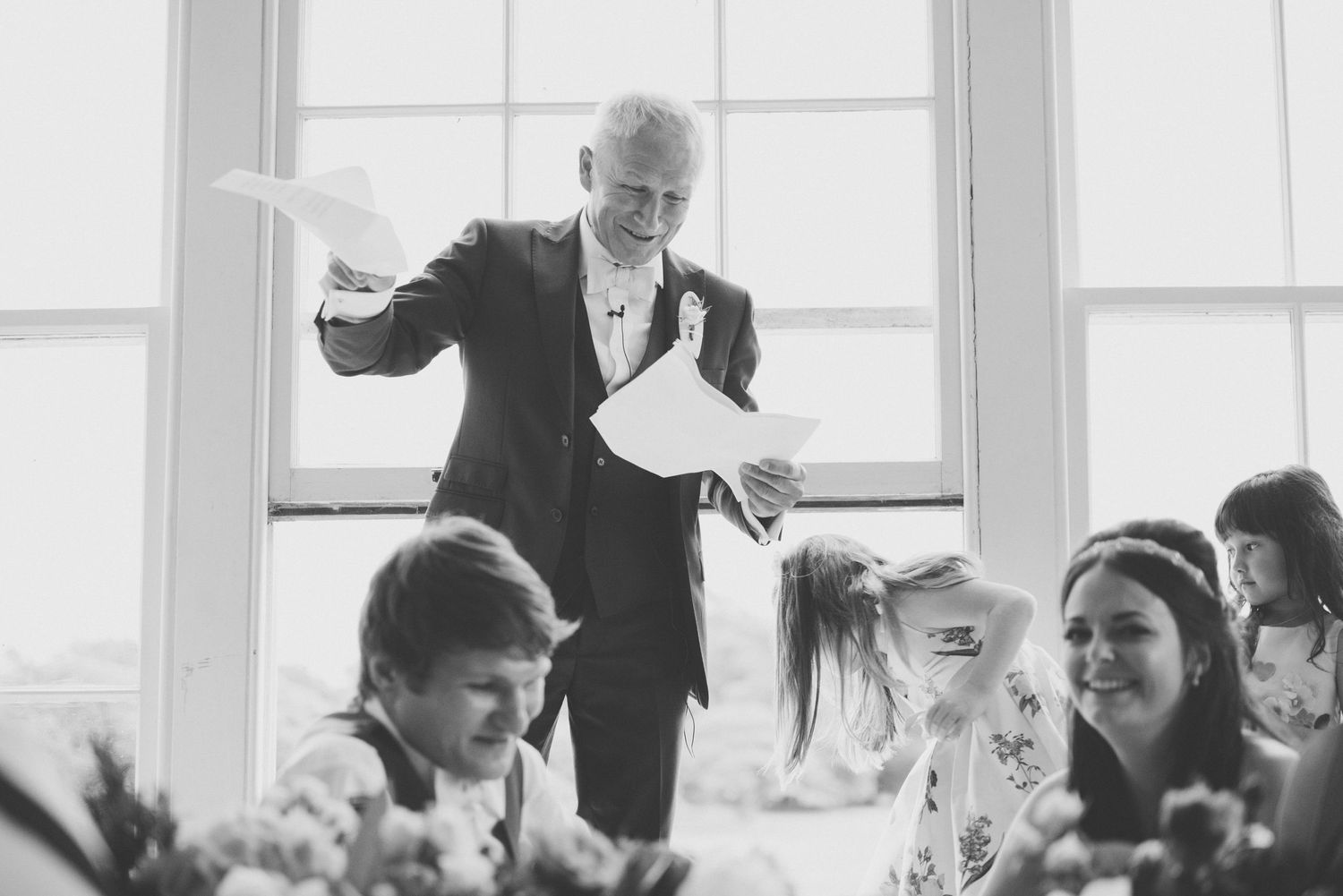 Black and white candid shot of animated speech during wedding reception.