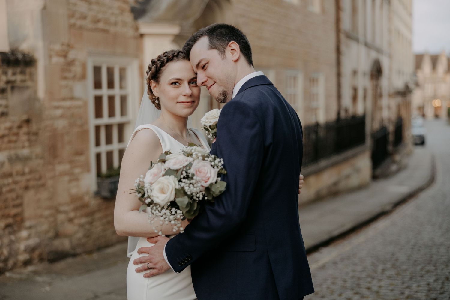 An intimate wedding portrait on a historic street with stone buildings.