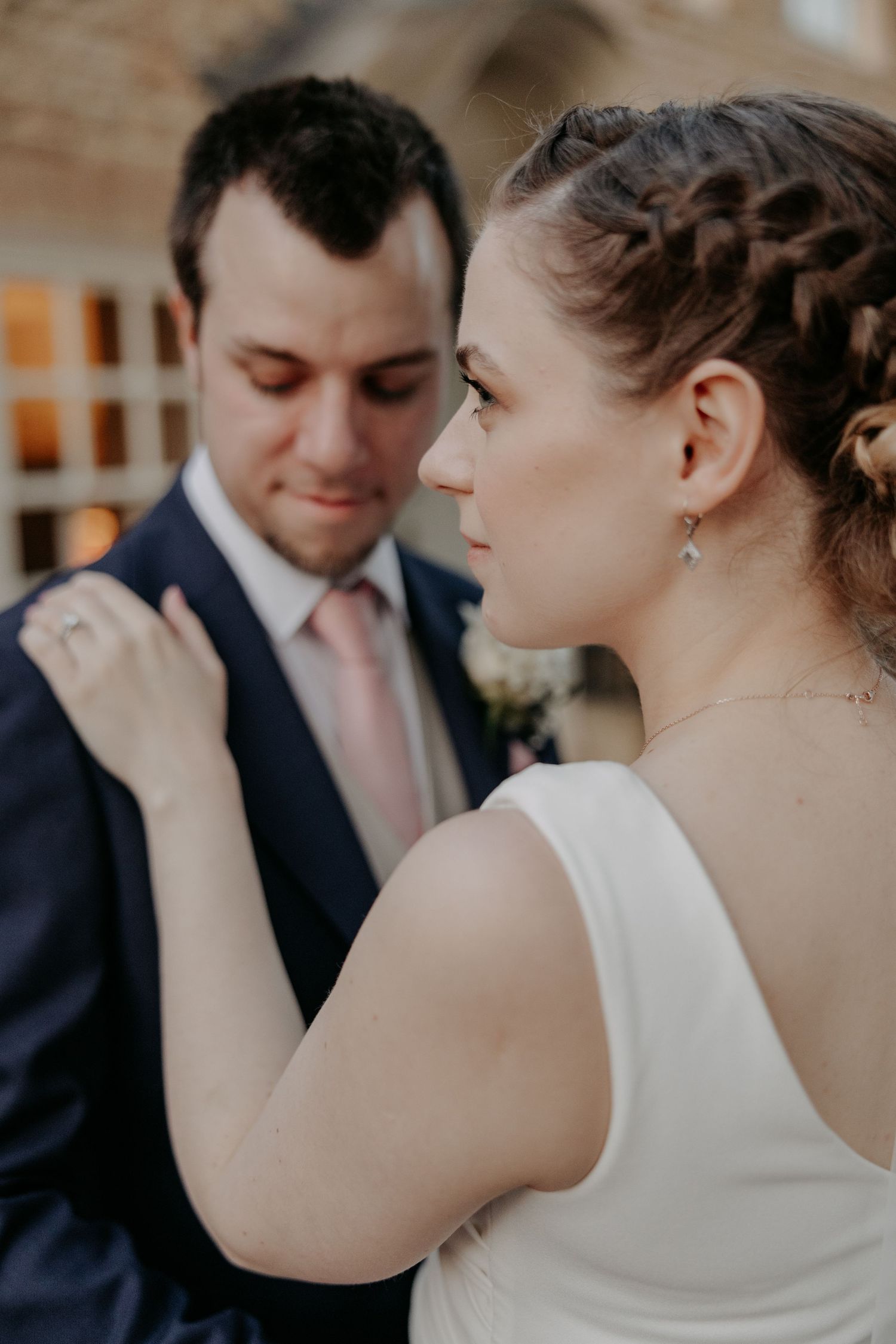 Intimate moment between bride and groom with detailed hairstyling and formal attire.