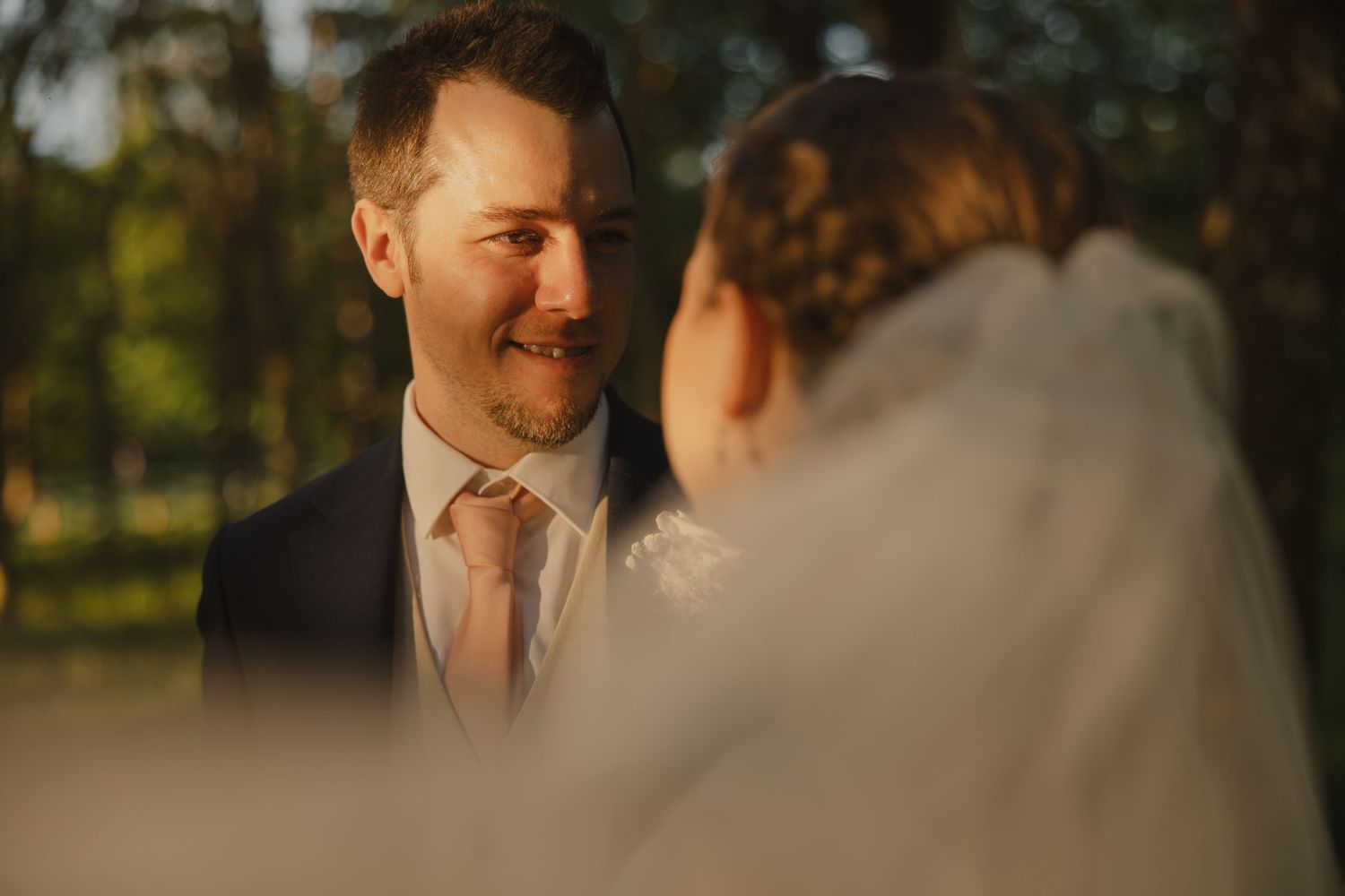 An emotional moment captured during an outdoor wedding ceremony in golden sunlight.