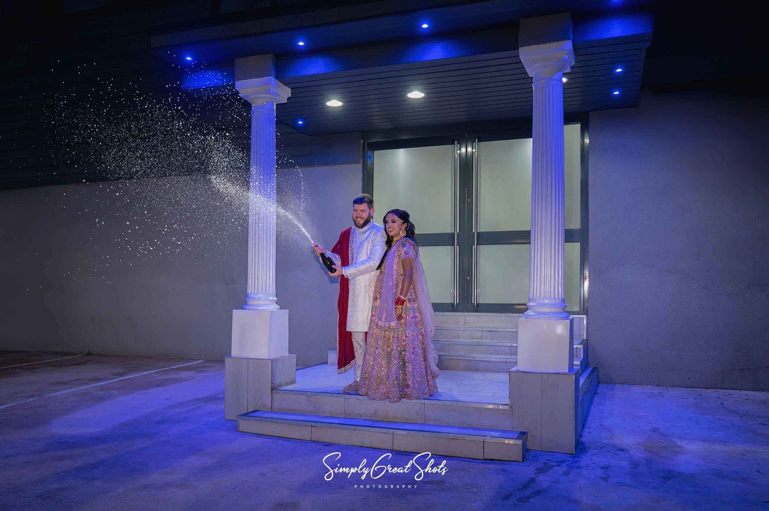 A married couple champagne spray photograph outside The White Daimond wedding venue in Coventry.