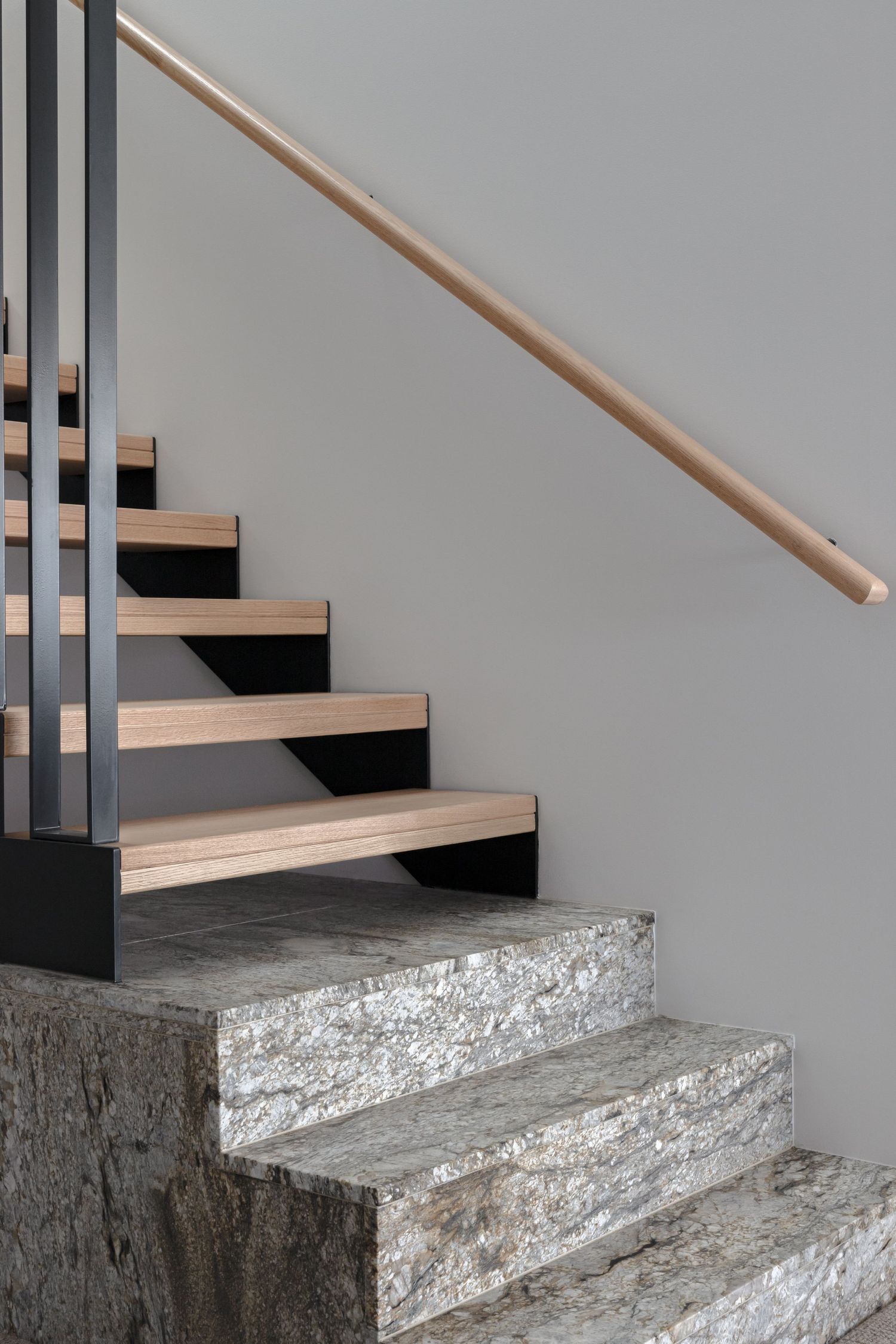 Modern staircase featuring wooden treads, black metal frame, and concrete base steps.