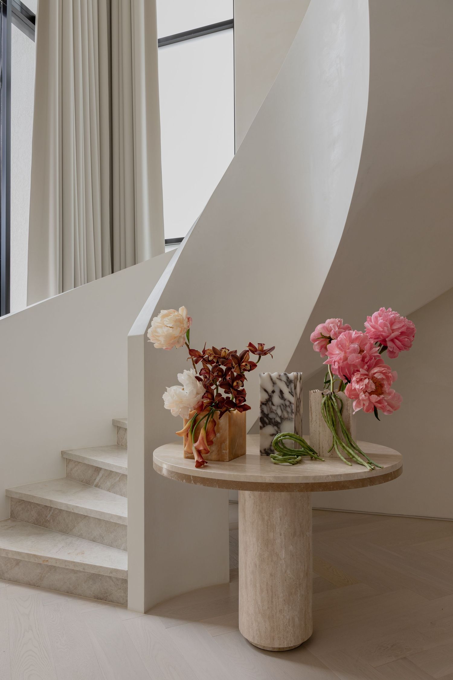 Round marble table with pink and white flowers in modern white interior space.