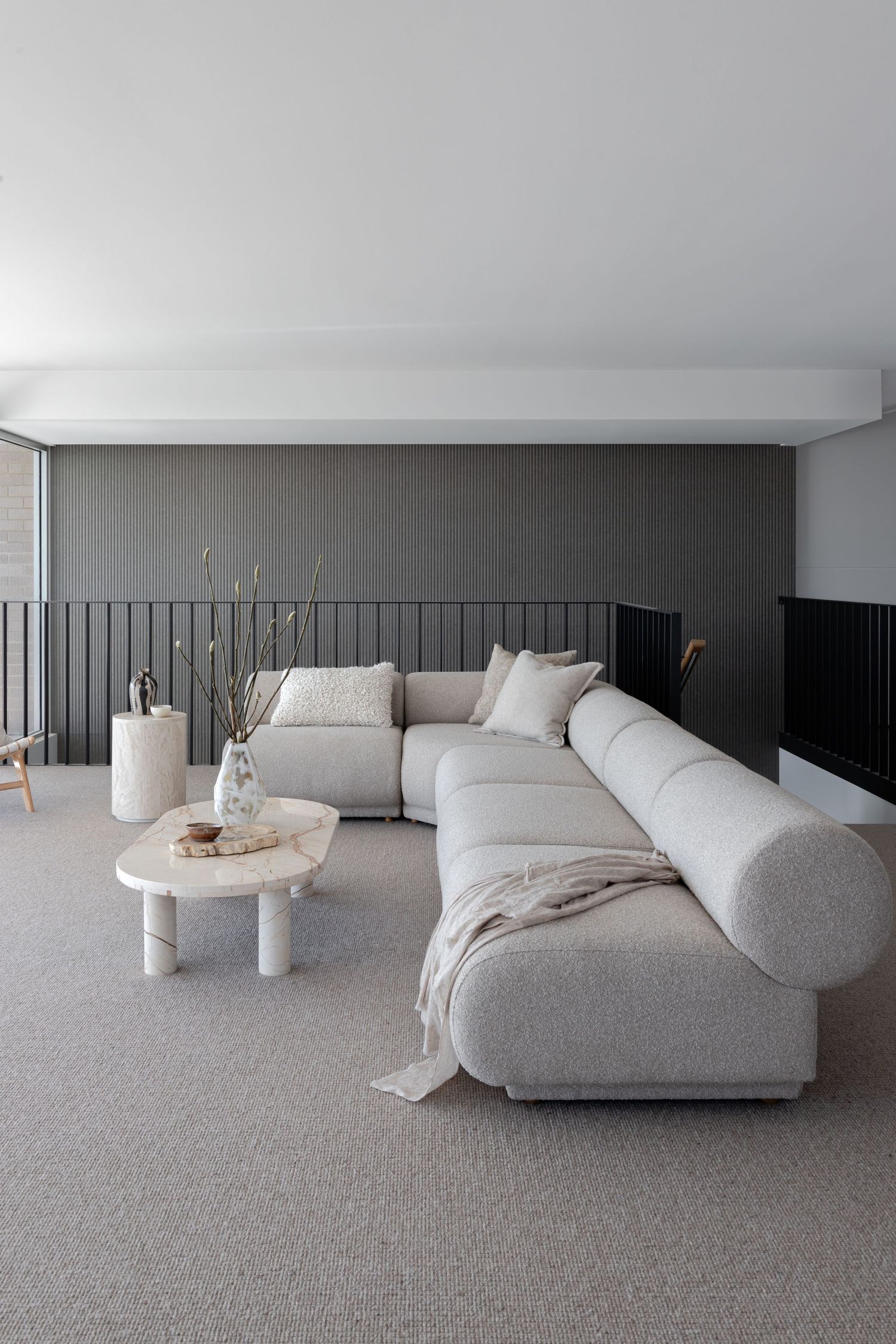 Contemporary living room with large grey sectional sofa and modern round coffee table against paneled wall.