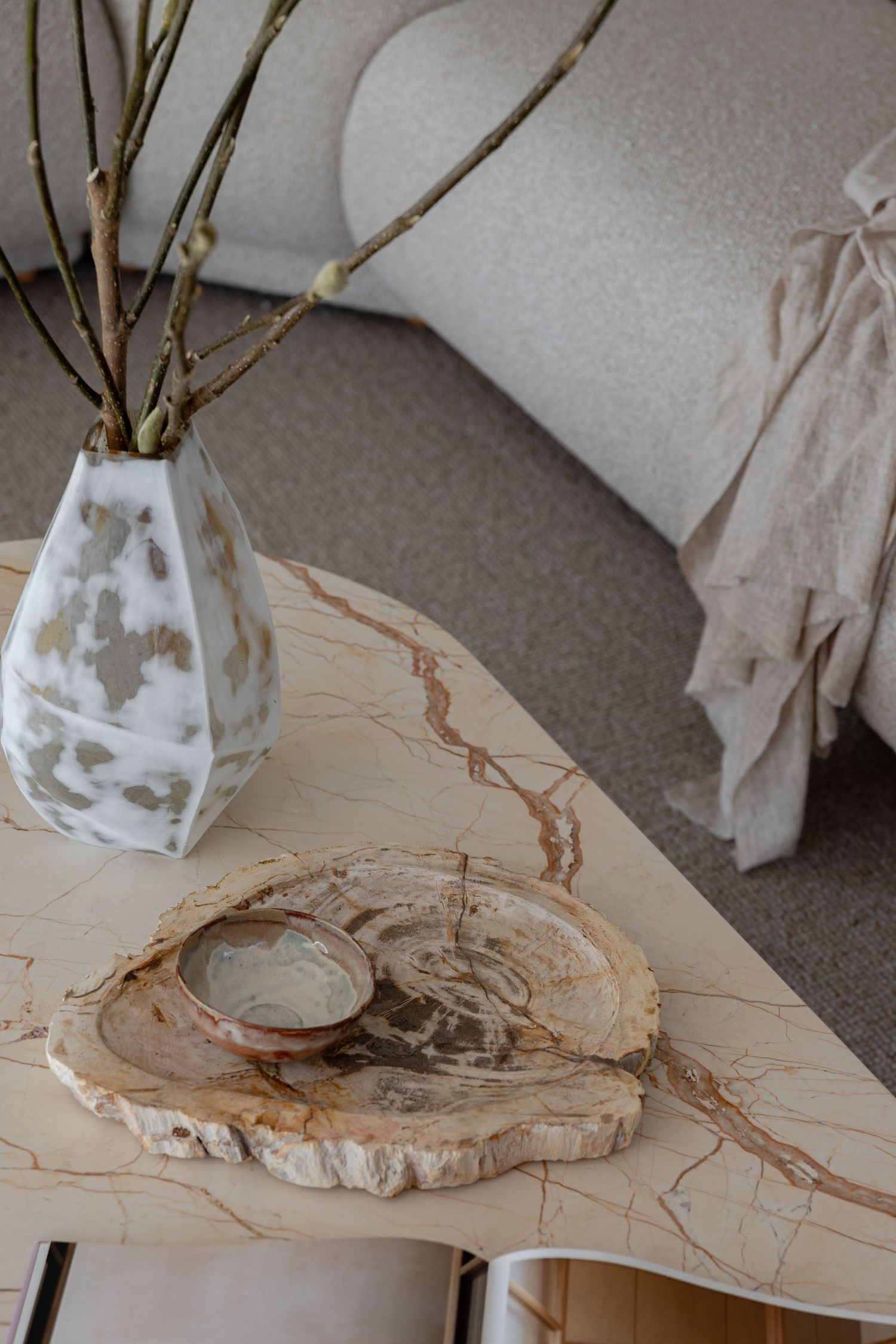Decorative vignette with marble coffee table, geometric vase, and natural wood slice accent.