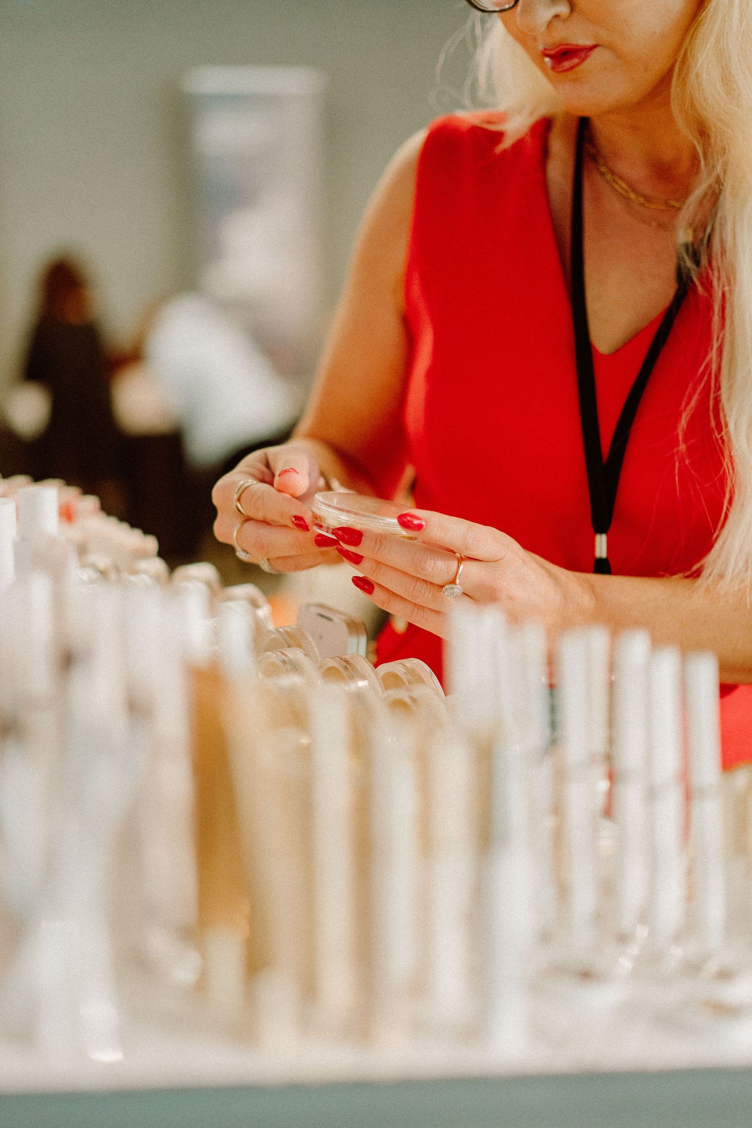Person in red top with bright red nails arranging drinks at an event.