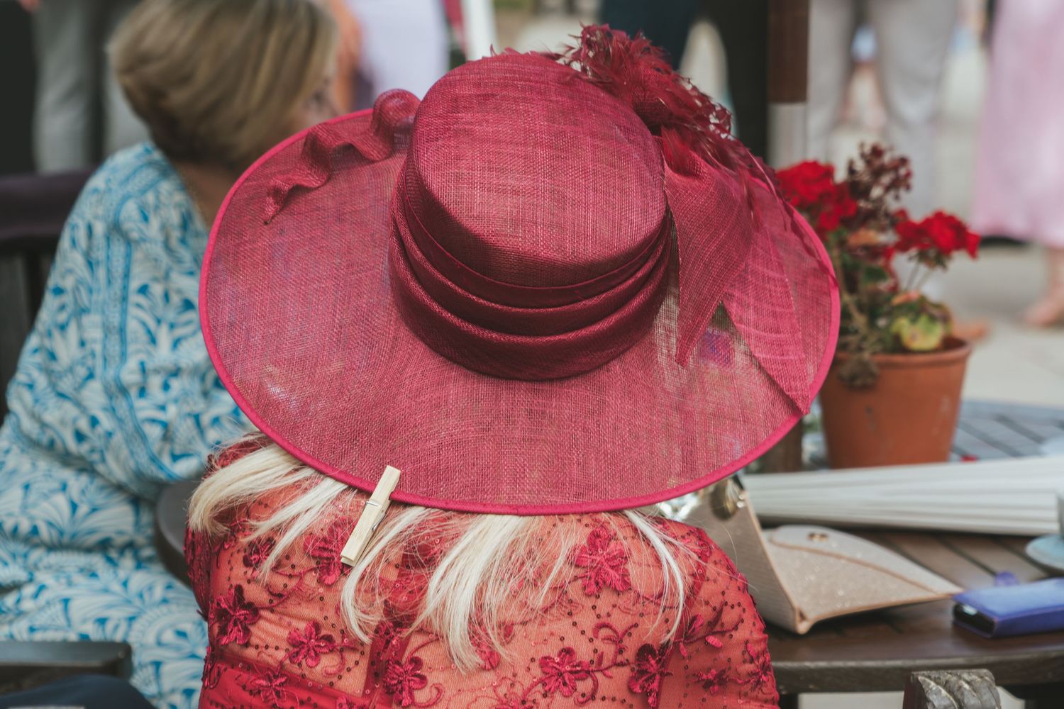 Person wearing a red wide-brimmed hat and floral dress viewed from behind.