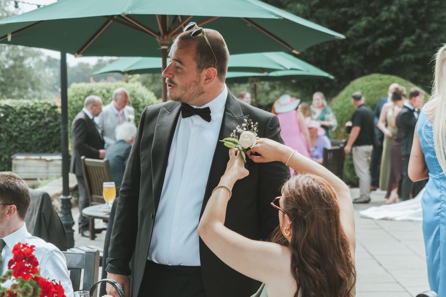 A couple shares a playful moment during an outdoor wedding reception under green umbrellas.