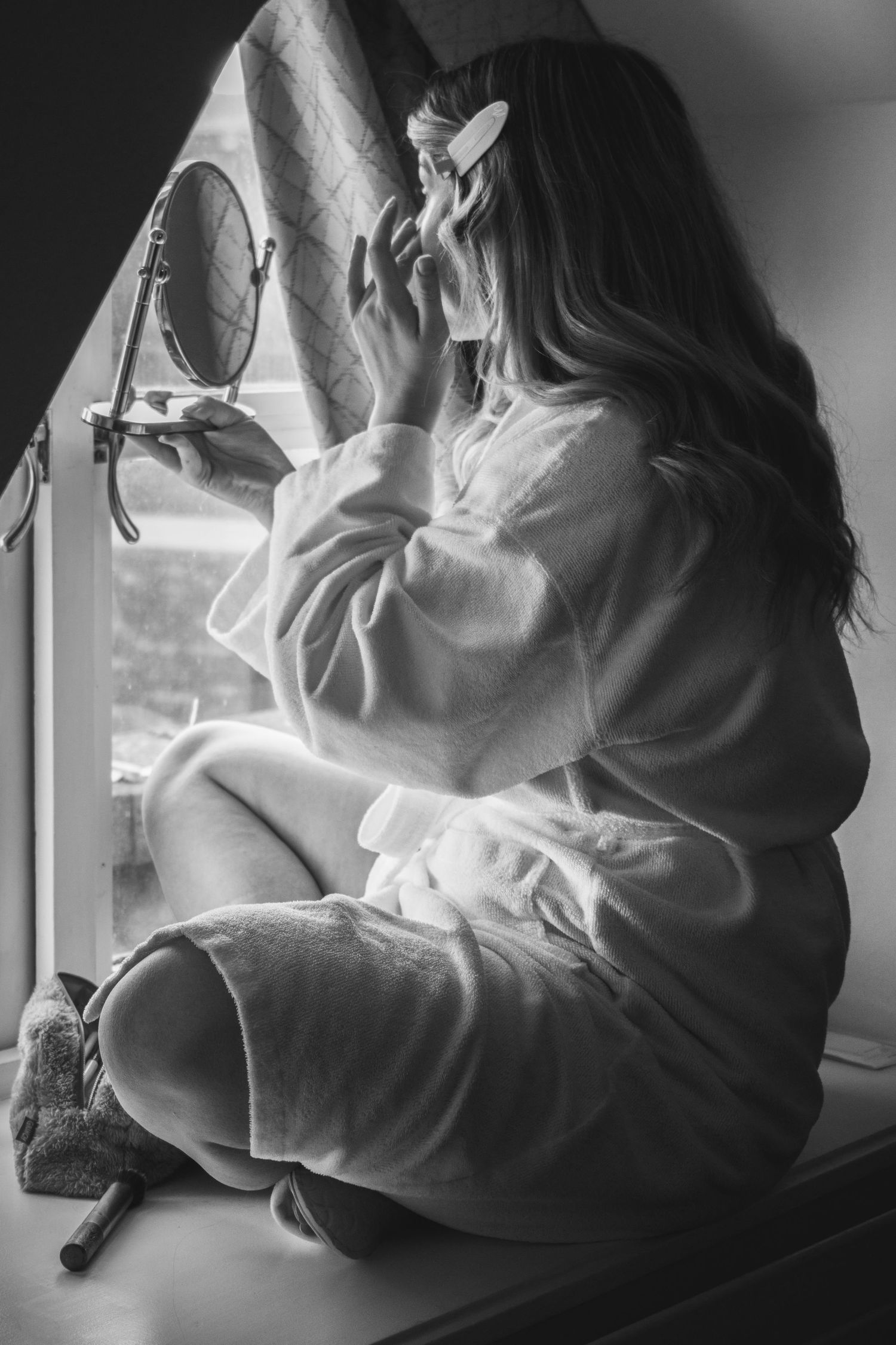 Artistic black and white photograph of person sitting by window in contemplative pose.