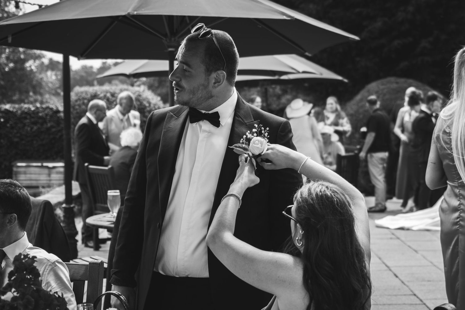 A formal reception moment captured in black and white under patio umbrellas.