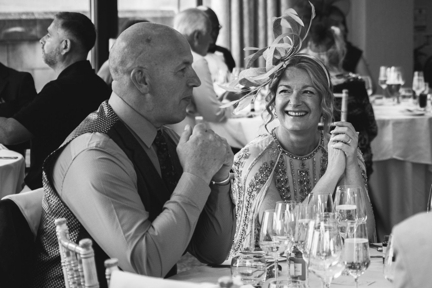Black and white photo of couple laughing together at formal dinner event.