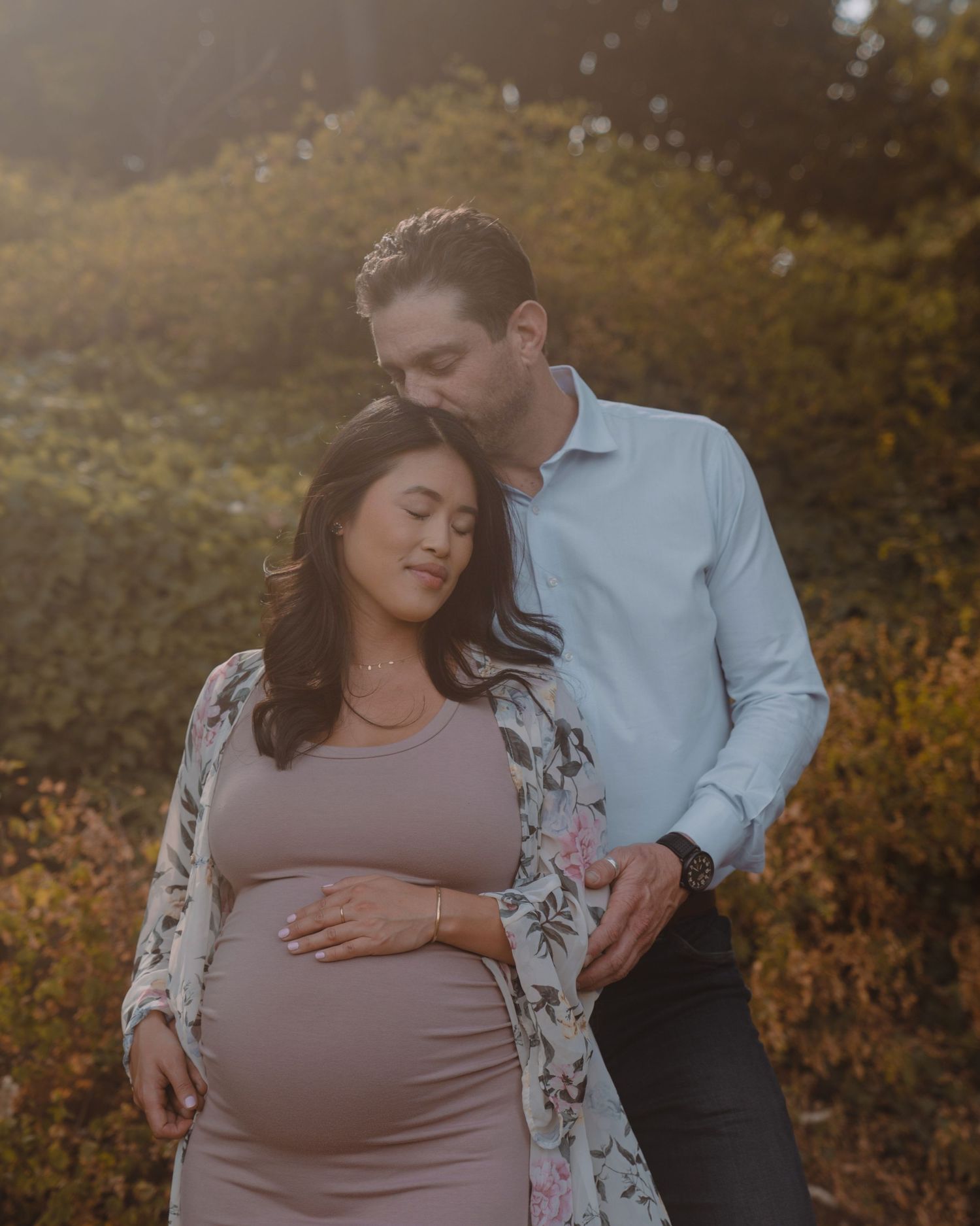 Maternity photo with couple in sunset light against autumn foliage.