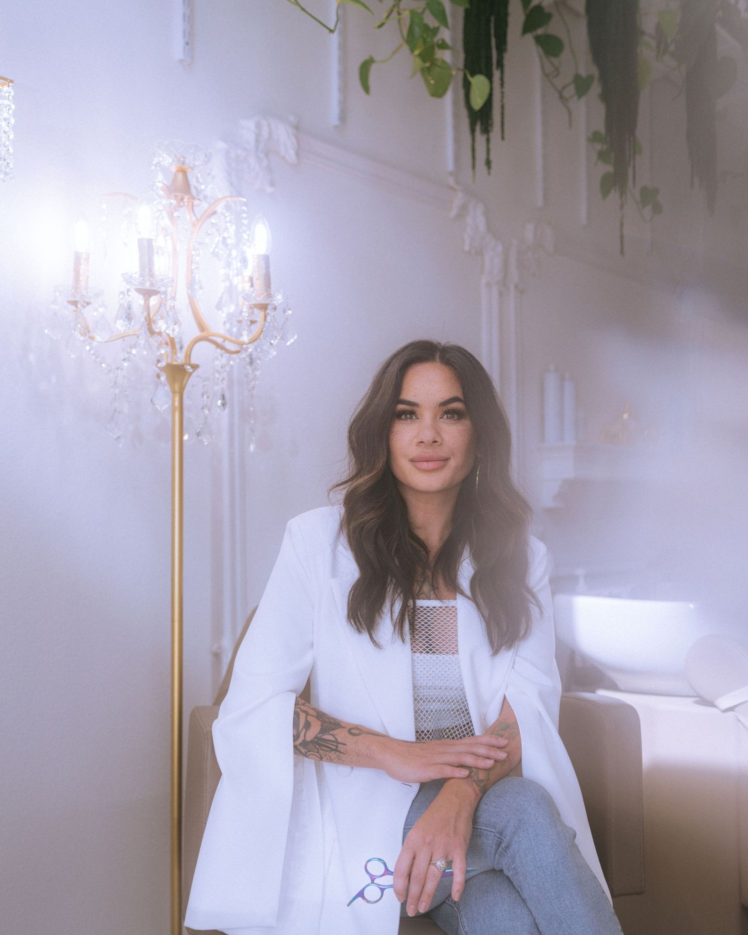 Ethereal portrait by ornate gold lamp with white blazer in dreamy lighting.