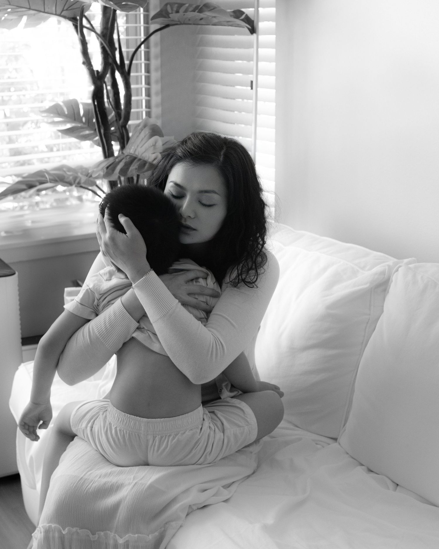 Intimate black and white photo showing tender moment in bedroom setting.
