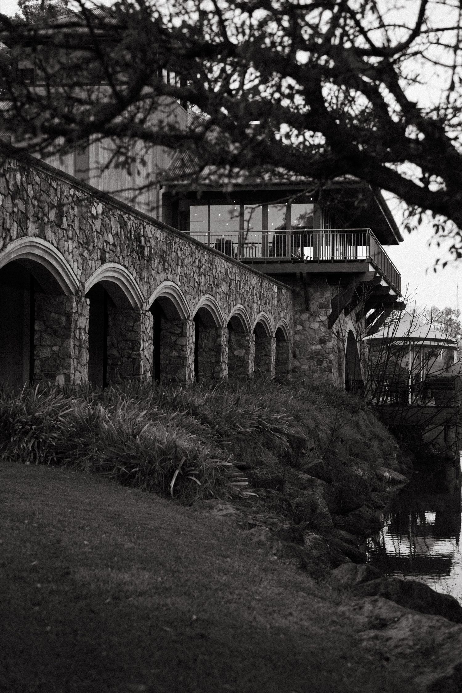 A series of gothic-style stone arches with overgrown plants along a building's exterior in black and white photography at Millbrook Winery