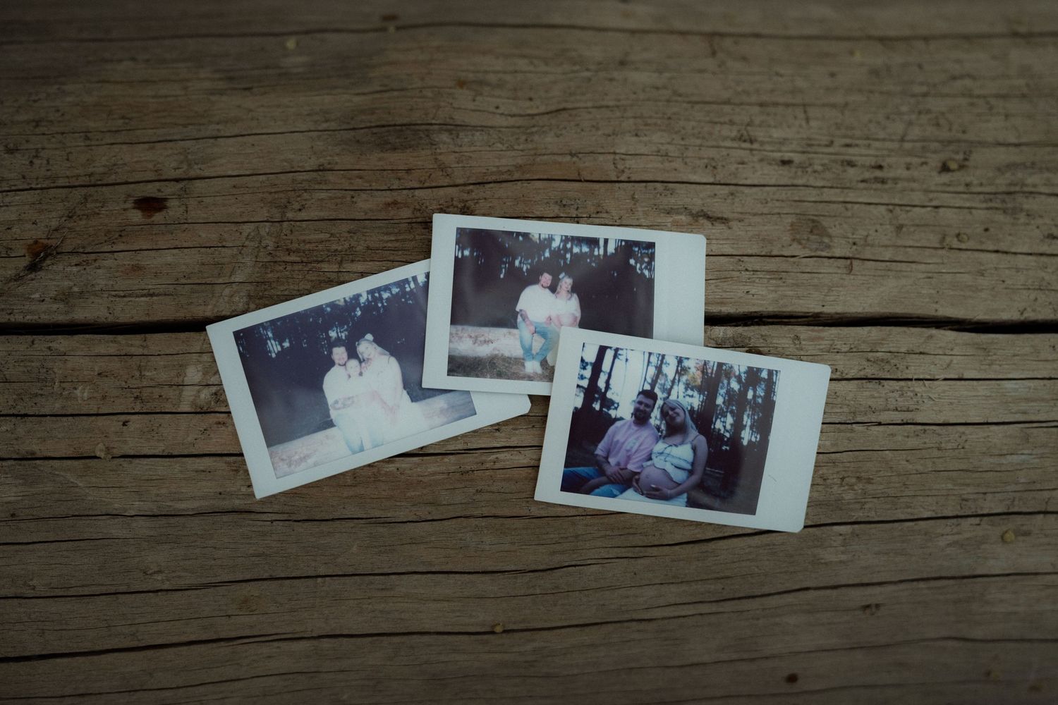 Three vintage polaroid photographs displayed on rustic wooden surface.