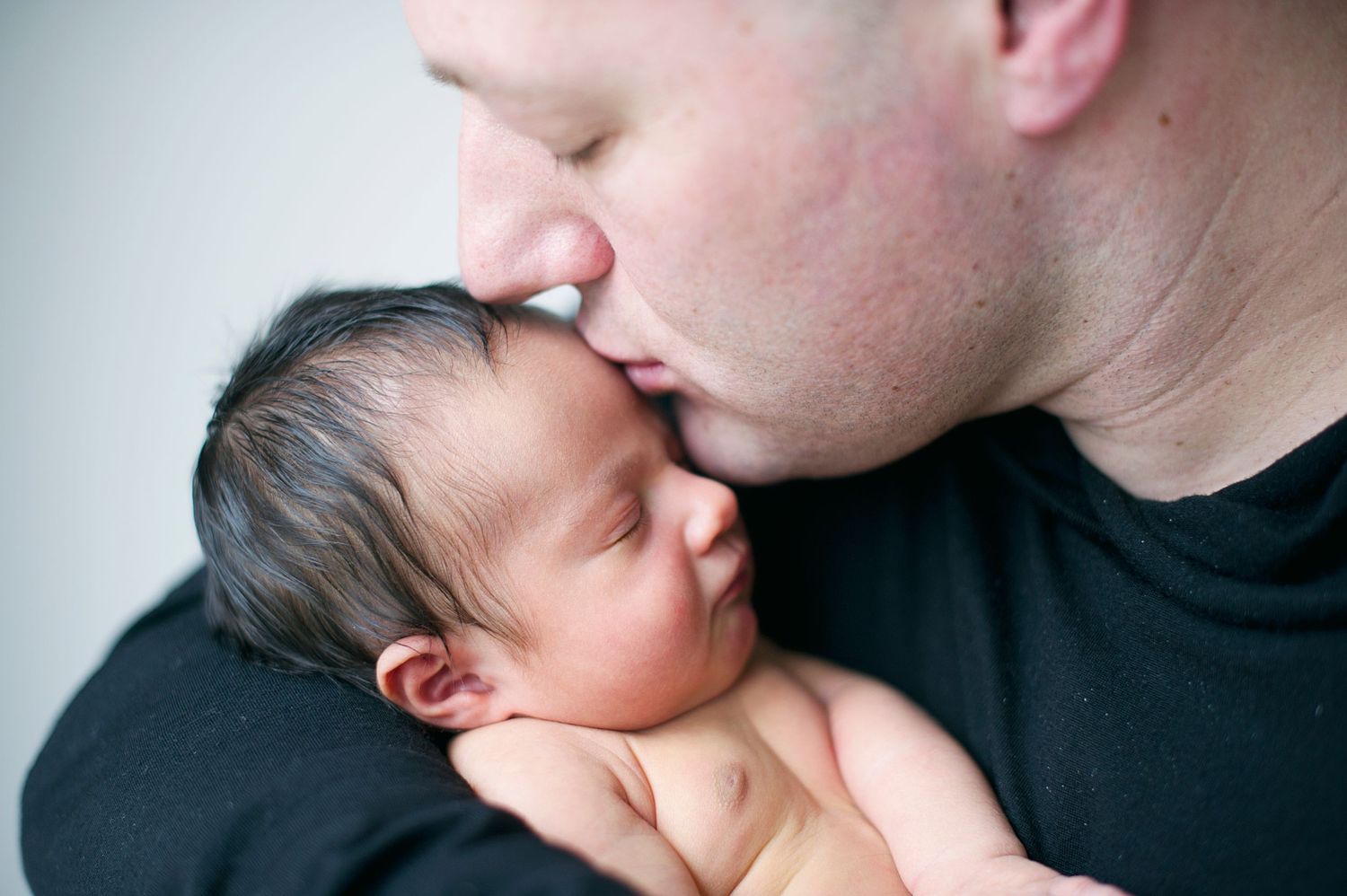 Dad kissing newborn baby on the head, captured by Phoebe Lee Photo in Toronto.