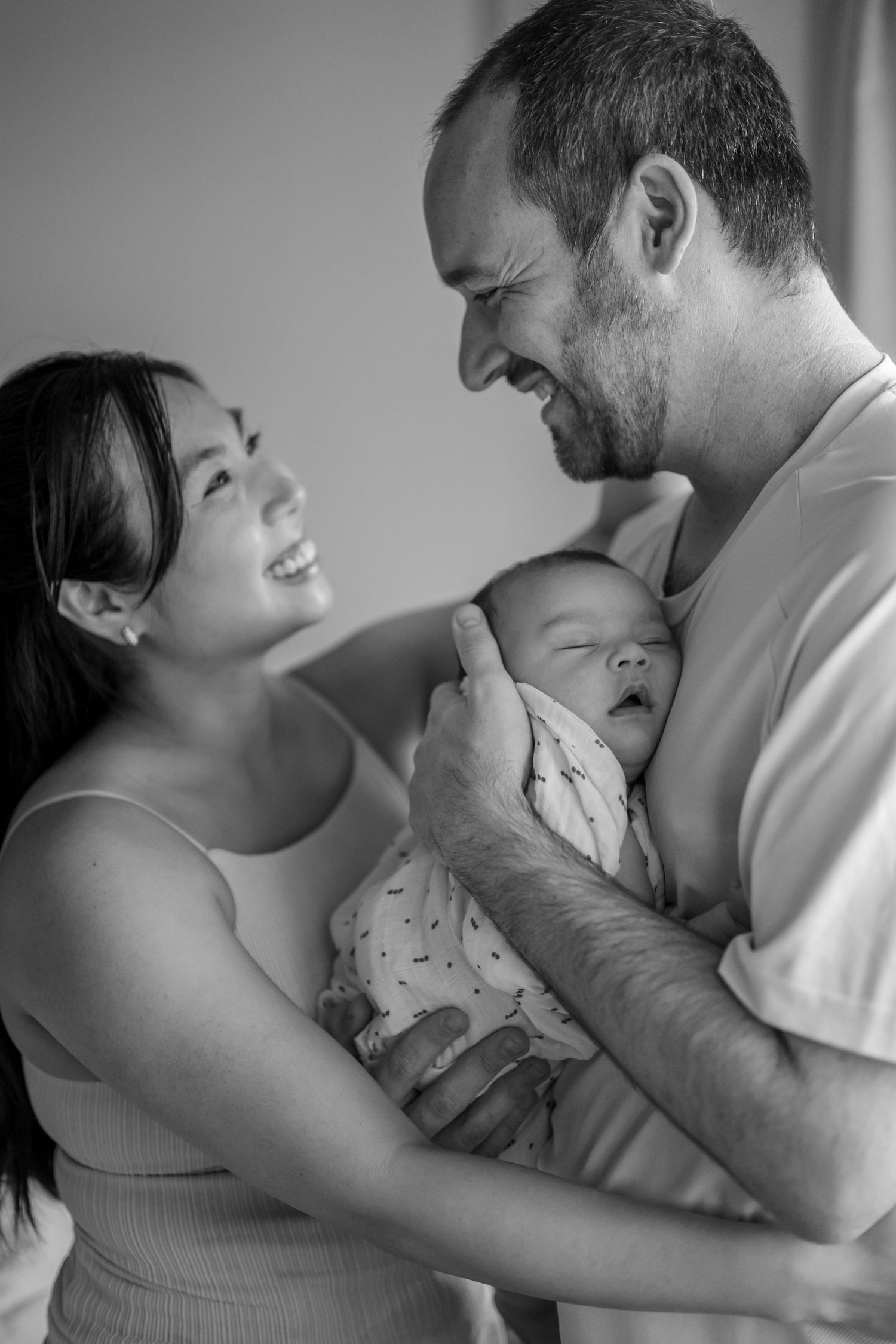 A tender black and white photo showing intimate moments between parents holding their baby. Family photography by Phoebe Lee Photo.