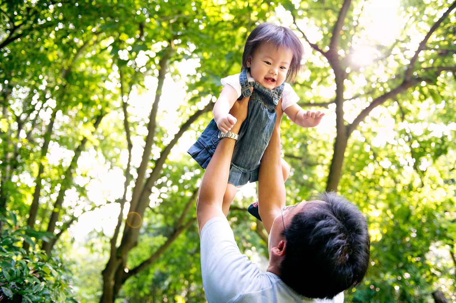 Dad playfully lifting his toddler girl in a sunny Toronto park, captured by Phoebe Lee Photo