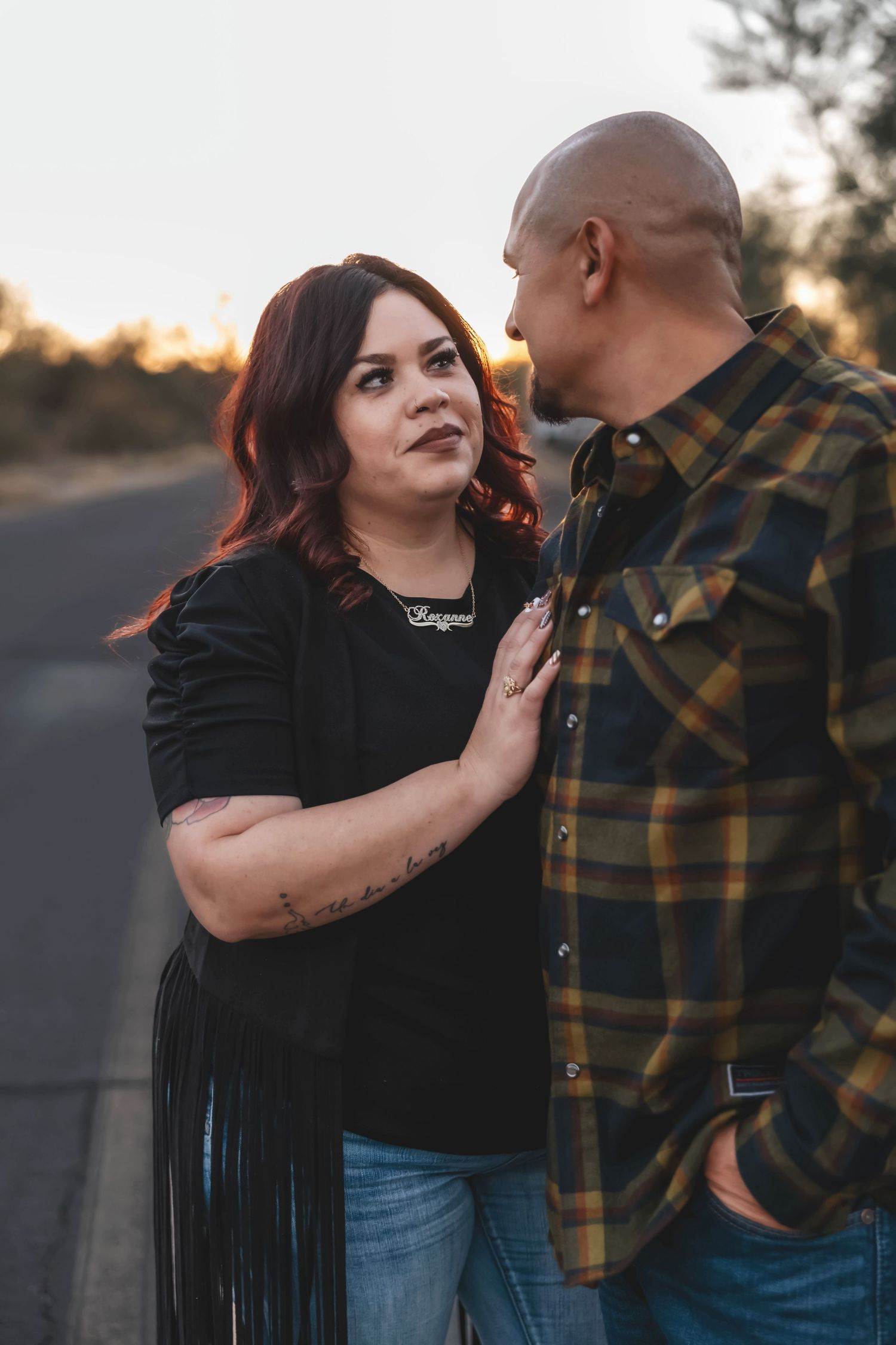 Couple in casual attire sharing intimate moment on desert road at sunset.