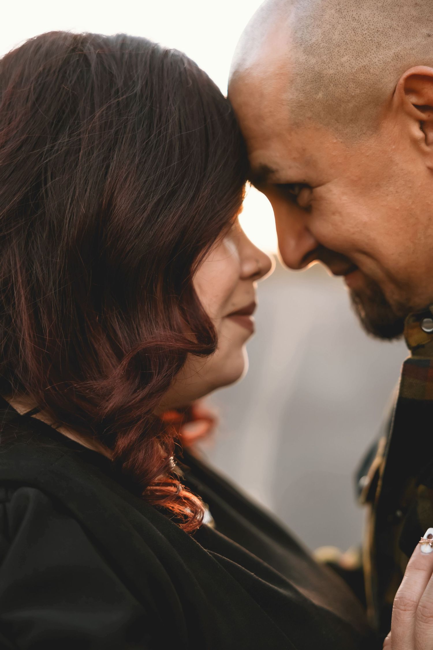 A romantic close-up portrait of an interracial couple sharing an intimate moment with their foreheads touching.