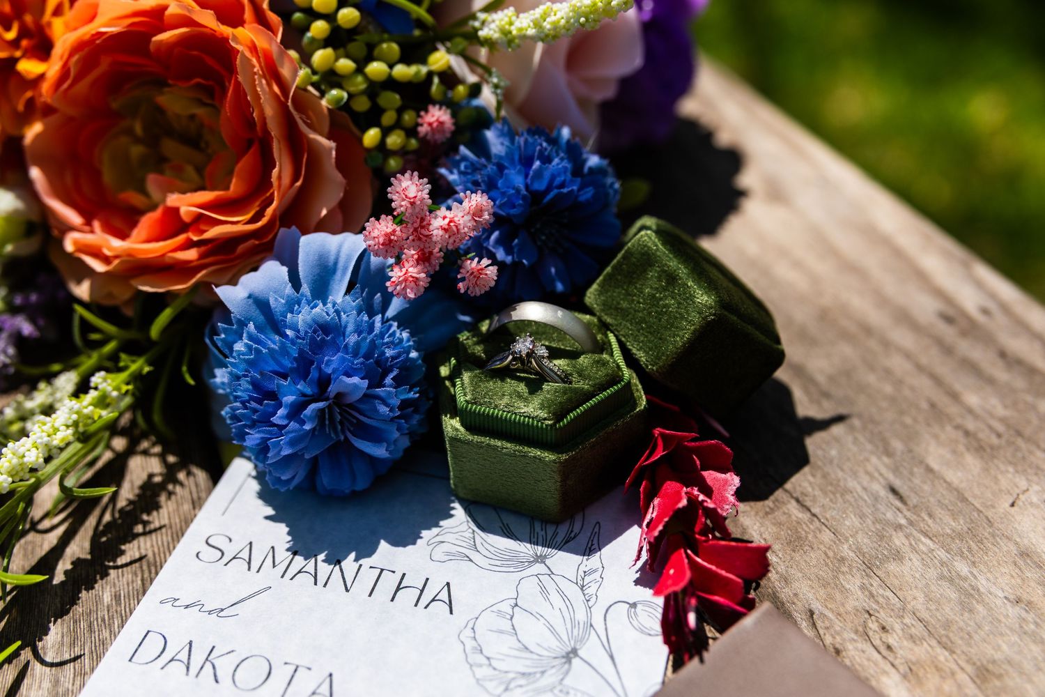 Place cards with elegant calligraphy sit among vibrant blue and coral floral arrangements on a rustic wooden surface.