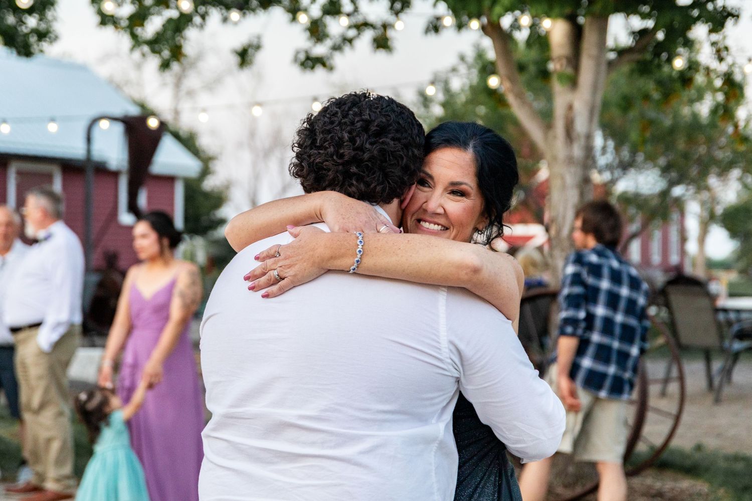 Wedding guests embracing during celebration outdoors.