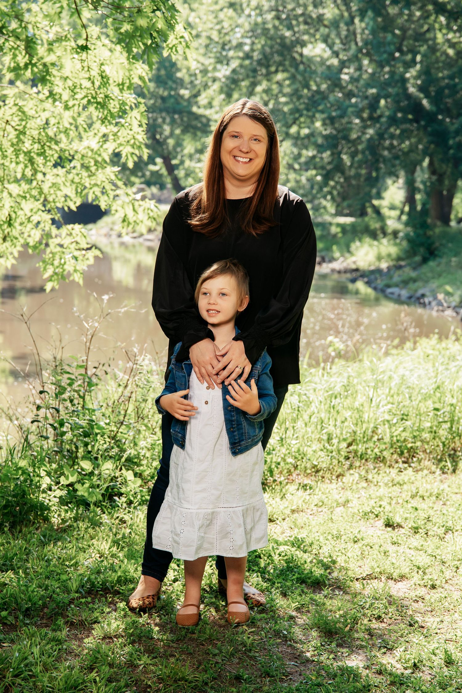 A scene of family togetherness captured outdoors by a peaceful pond on a bright summer day.