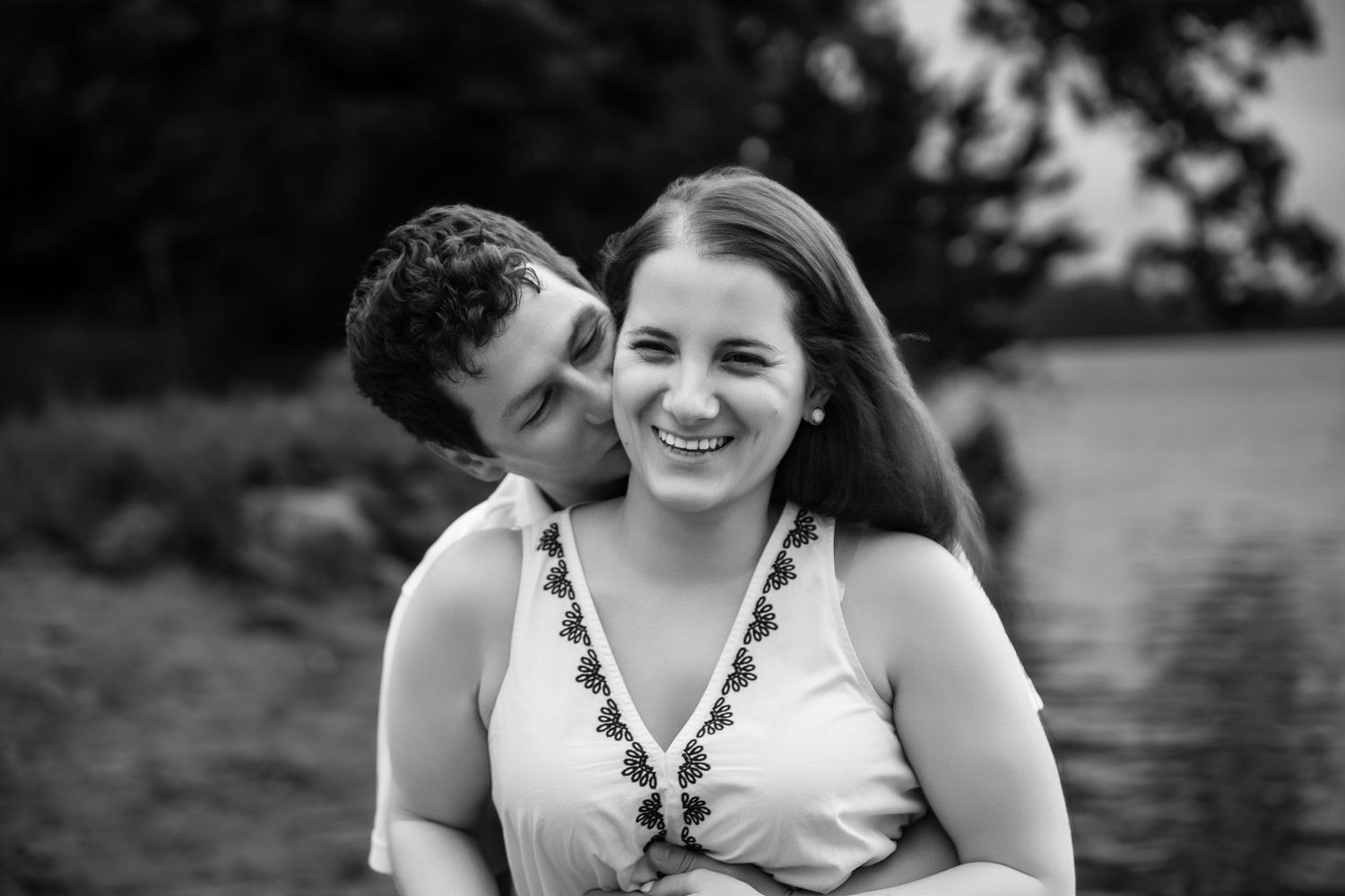 A romantic moment captured in black and white by the waterfront.