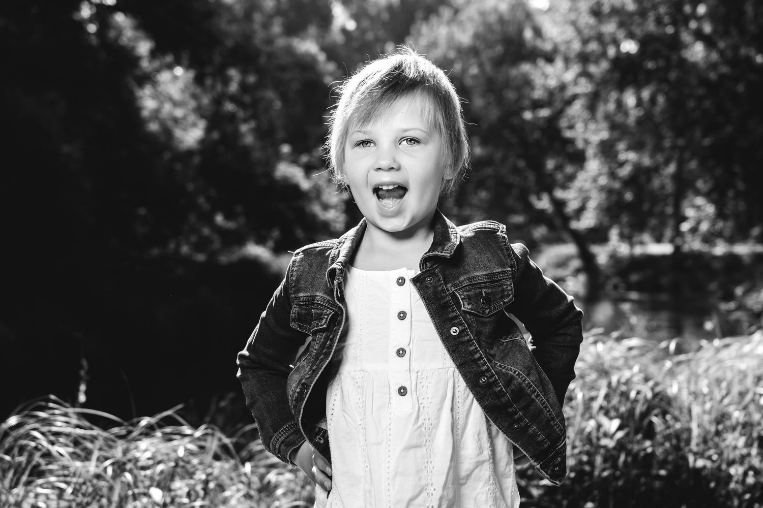 A black and white montage of multiple photos showing a young child in a formal white dress and dark vest outdoors.
