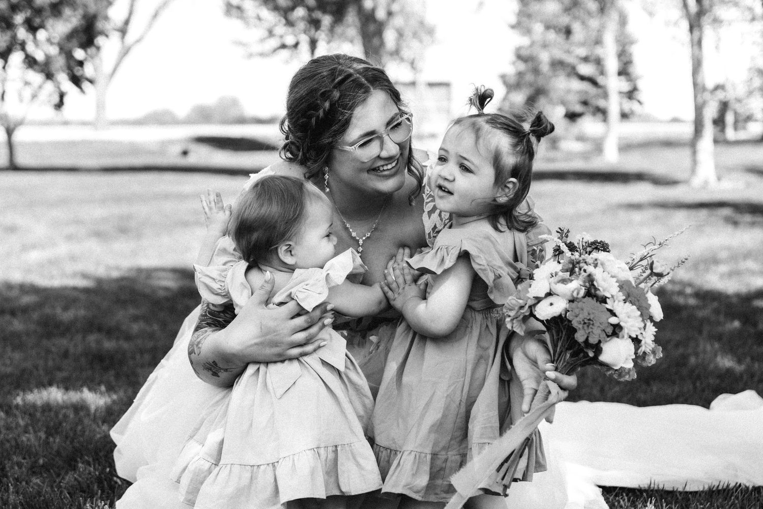 A tender moment captured in black and white showing embrace with flowers in outdoor setting.