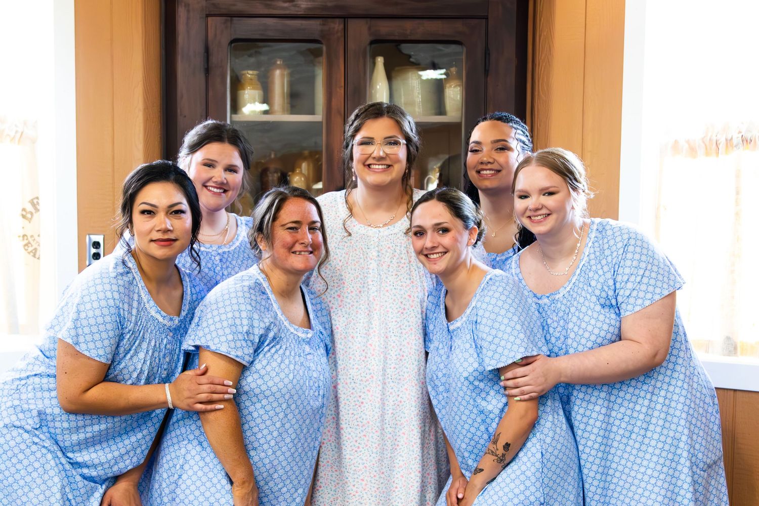 Healthcare workers wearing blue and white checkered uniforms pose together smiling in front of a building.