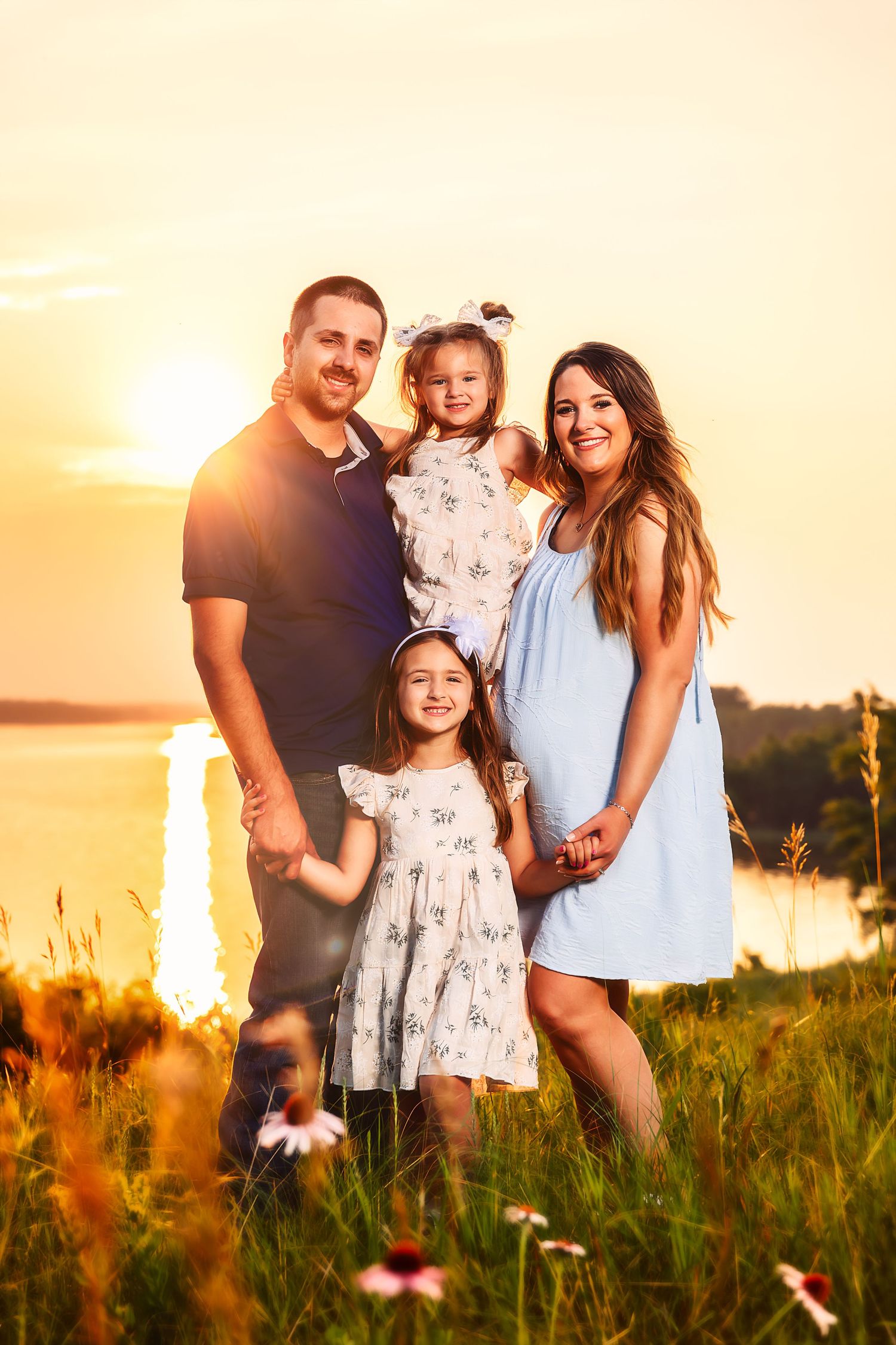 Happy family enjoying golden sunset together in summer meadow with tall grass and wildflowers in Western Minnesota