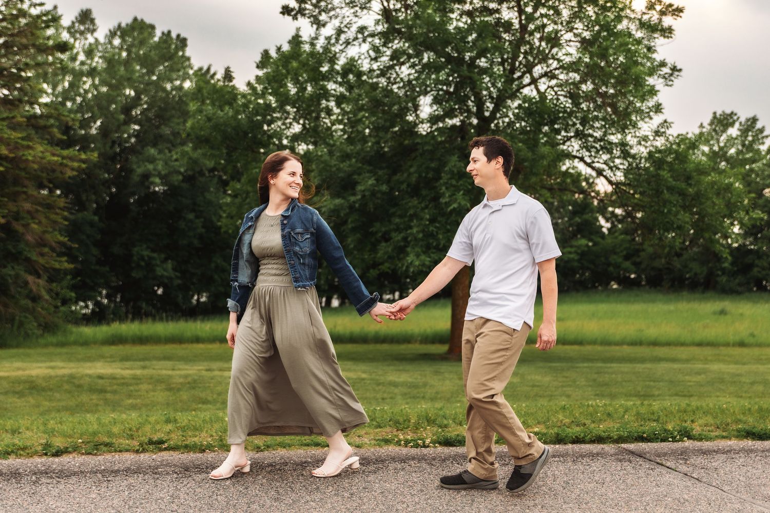 A sweet couple takes a romantic stroll together through a park setting during a sunny day.