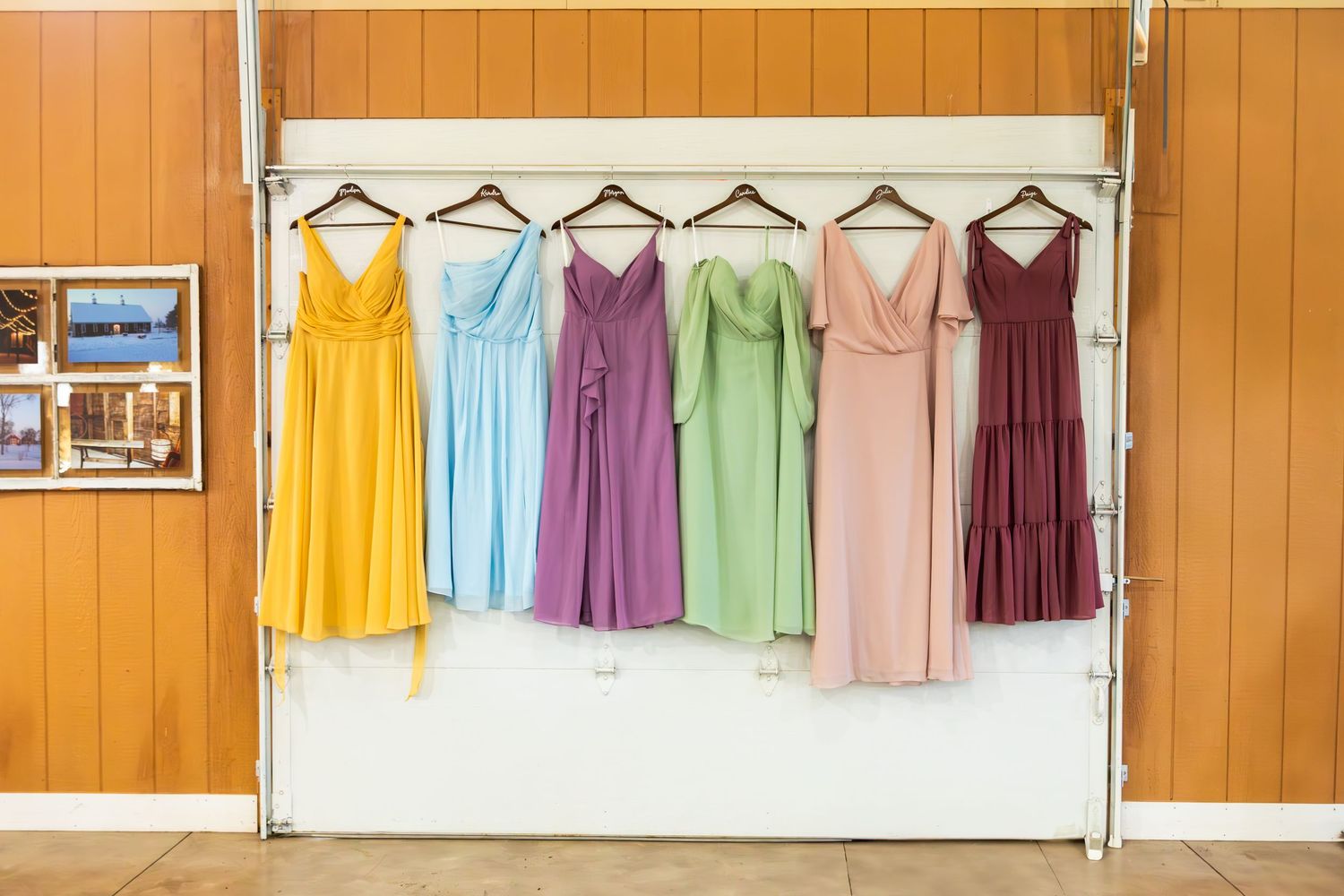 Colorful bridesmaid dresses in yellow, blue, purple, green, pink and burgundy hanging on display rack.