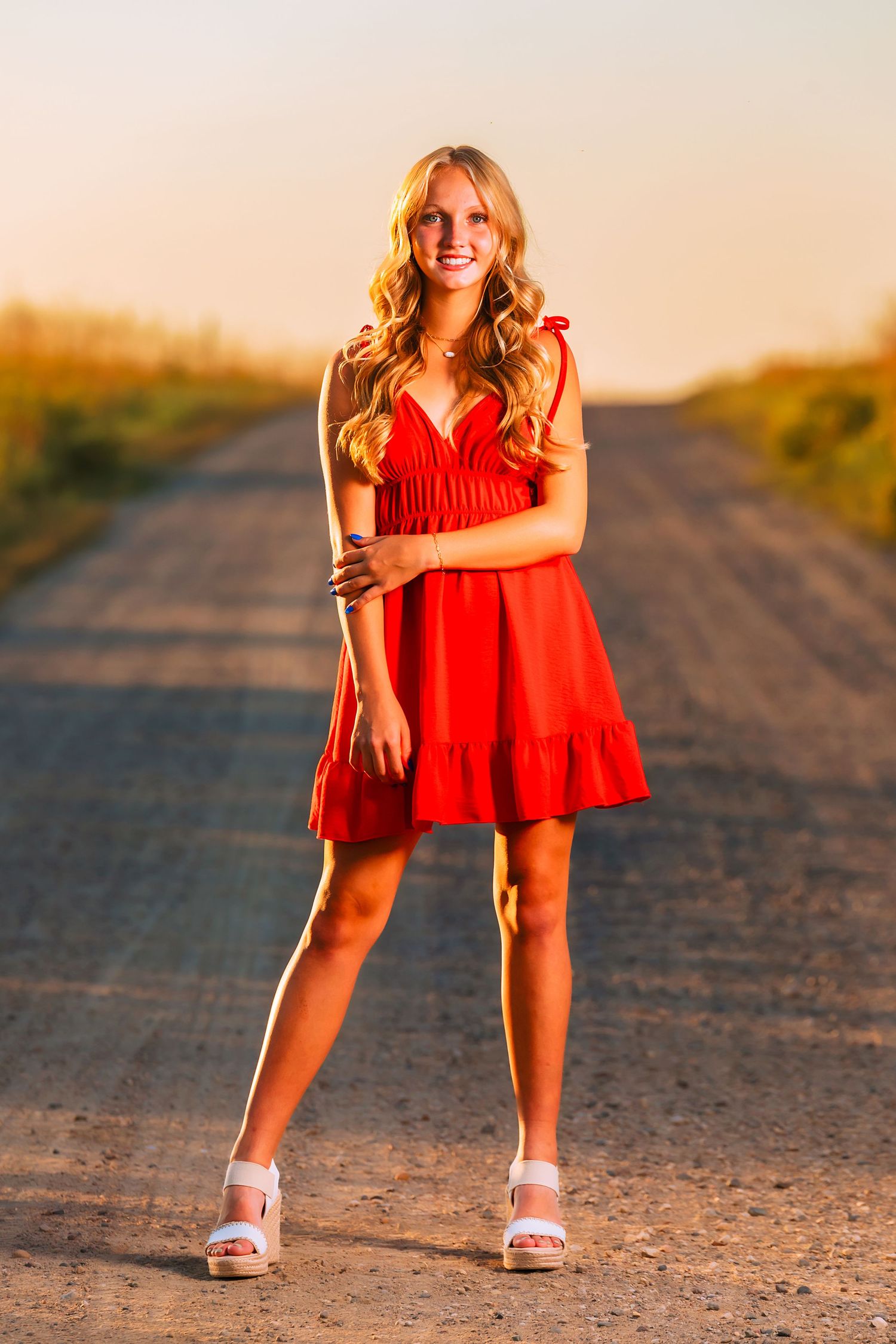 Lifestyle photos on a dirt path wearing a flowing red summer dress in golden hour lighting.
