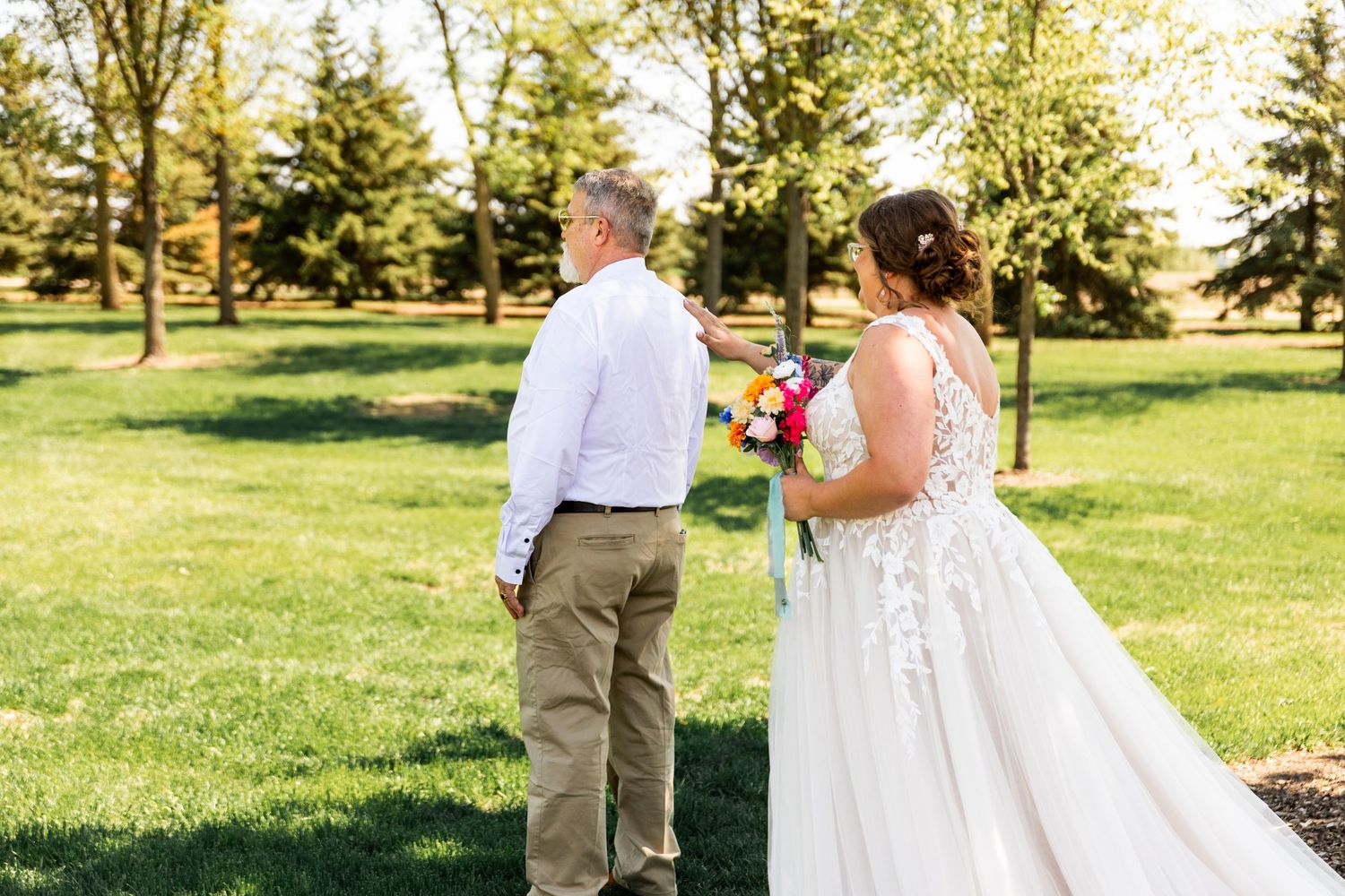 Wedding couple walking together on a sunny day in a grassy park setting.