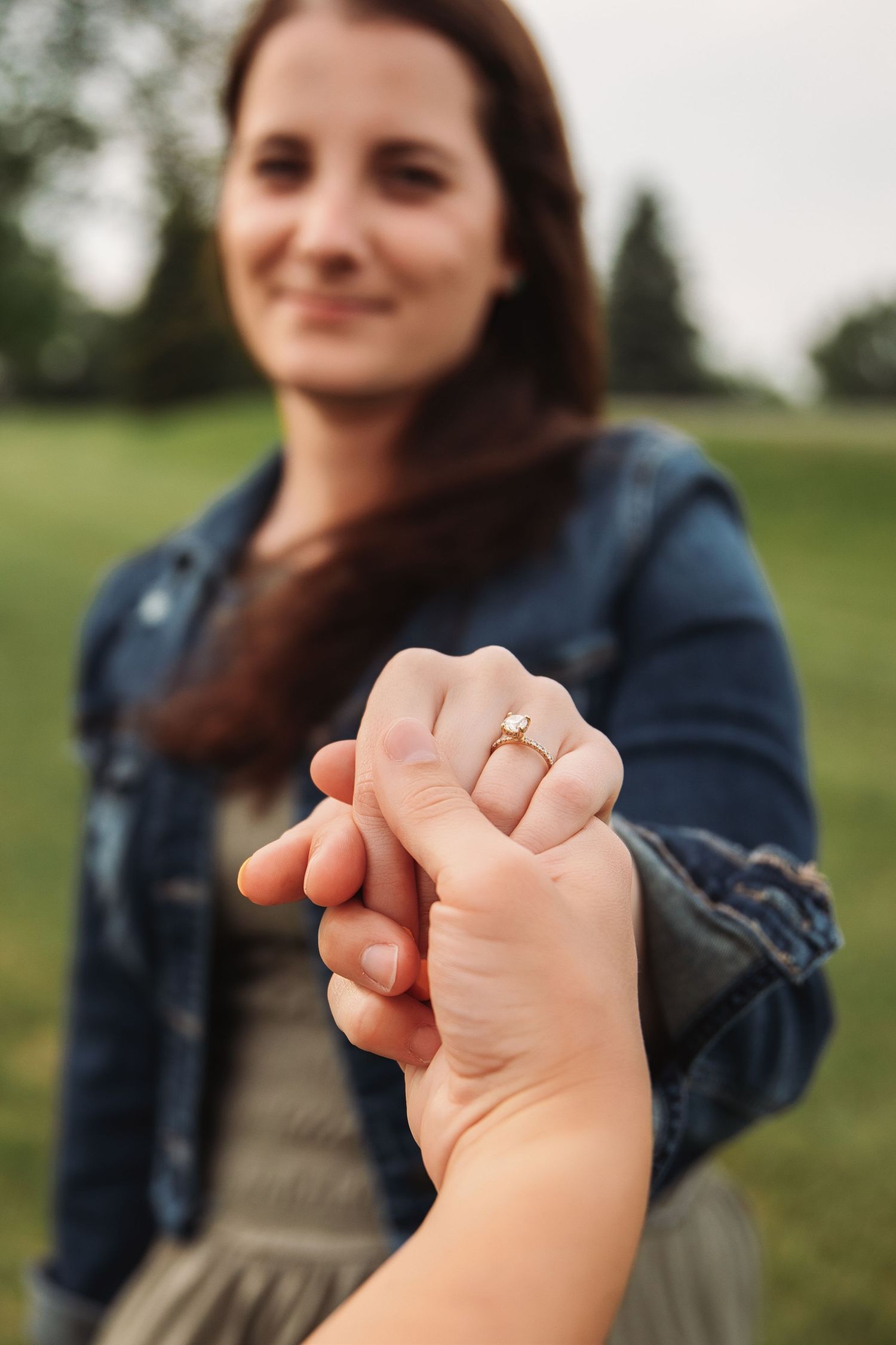 Close up shots showing hands gently clasped together while wearing a denim jacket in an outdoor setting.