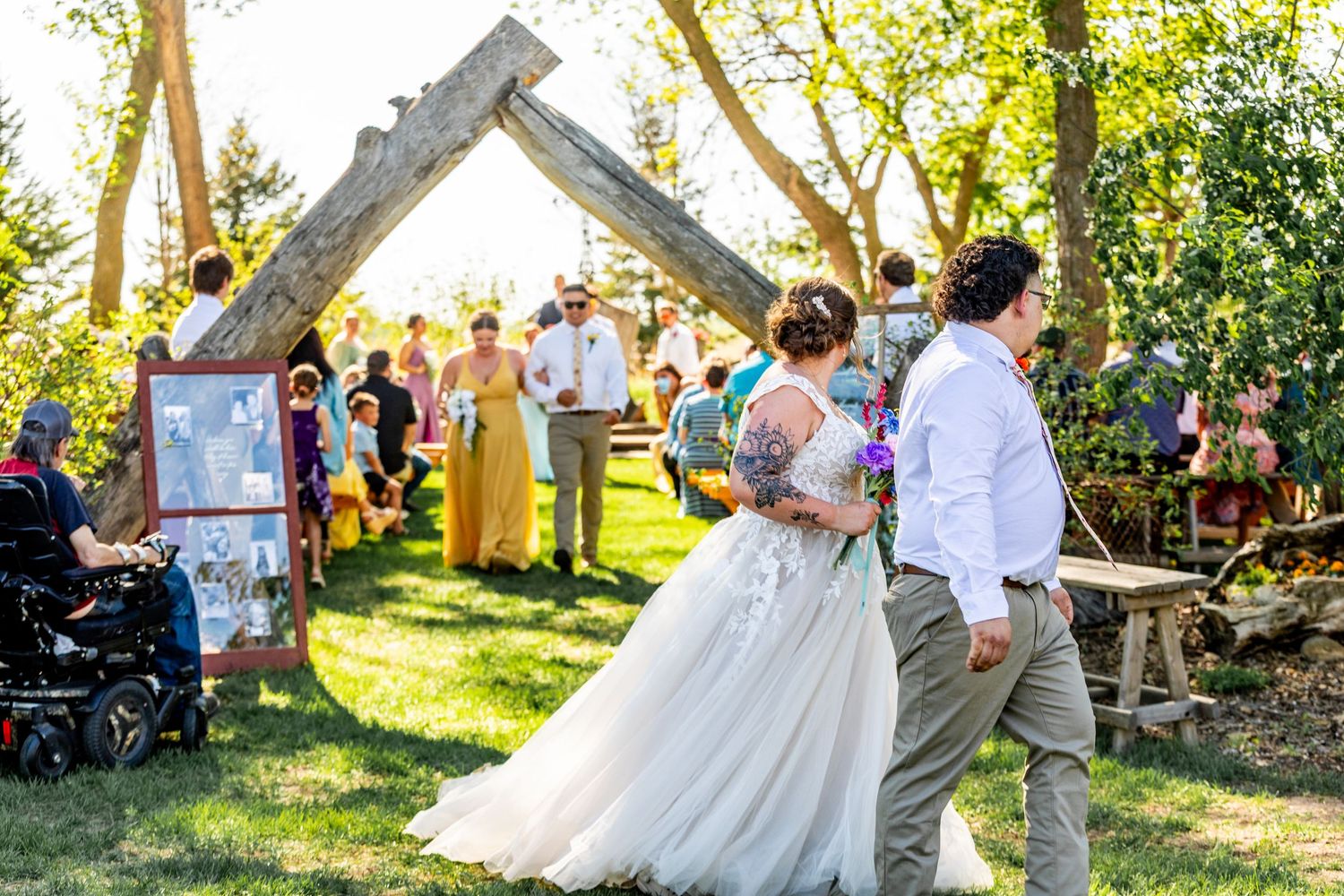 Outdoor wedding ceremony setup with white chairs and natural decor in a sunlit garden.