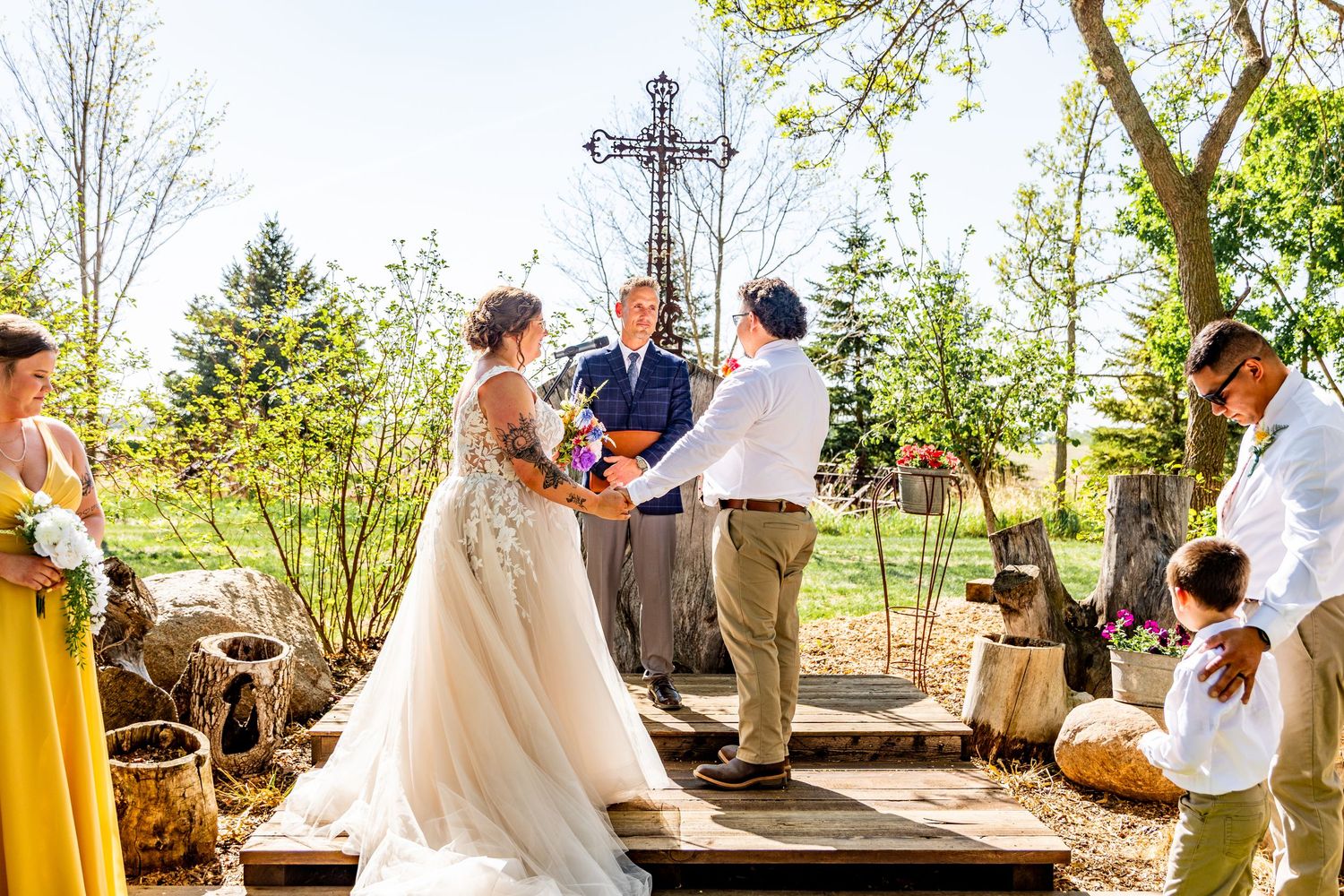 Outdoor wedding ceremony taking place in a garden setting with natural lighting and greenery.
