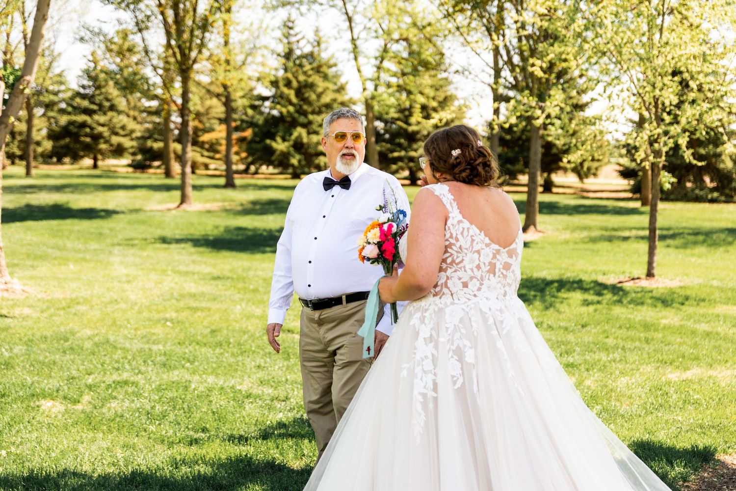 A couple shares their first look moment in a sun-drenched park during their wedding celebration.