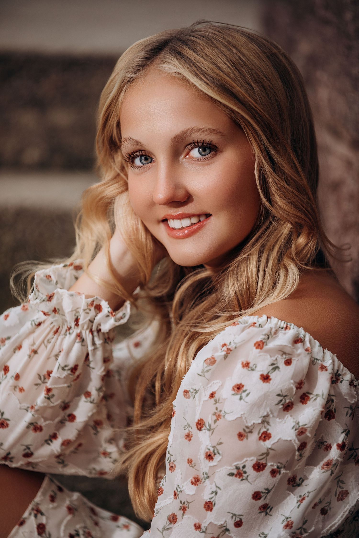 A close-up portrait shows wavy blonde hair, floral off-shoulder dress, and natural makeup.