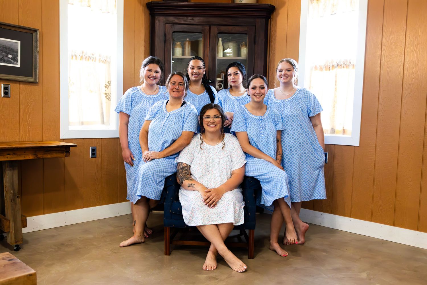 Wedding party members in light blue attire gather indoors for group photos.