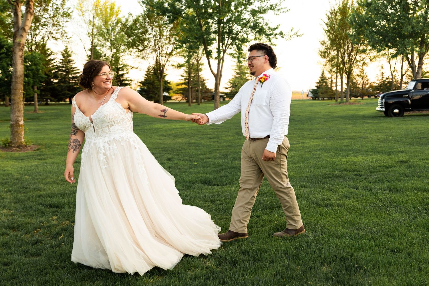 Couple dancing on grass at sunset during their wedding celebration.