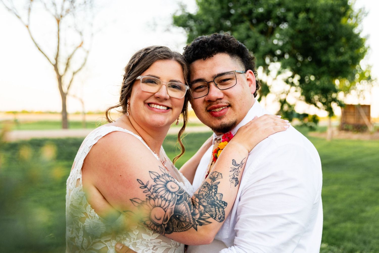 A joyful outdoor wedding portrait of a couple embracing and smiling at the camera.