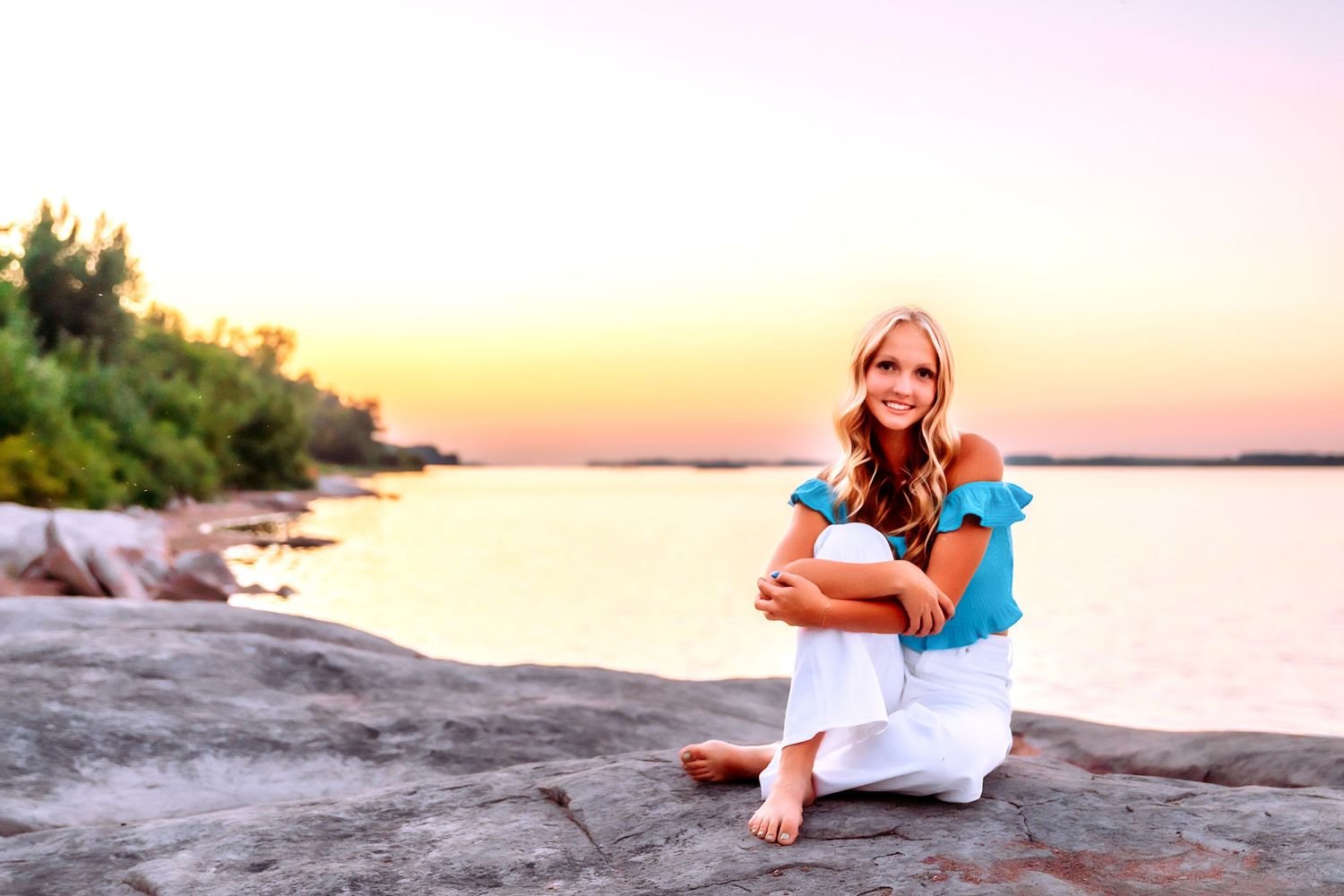 Casual waterfront portrait on rocky shoreline at sunset.