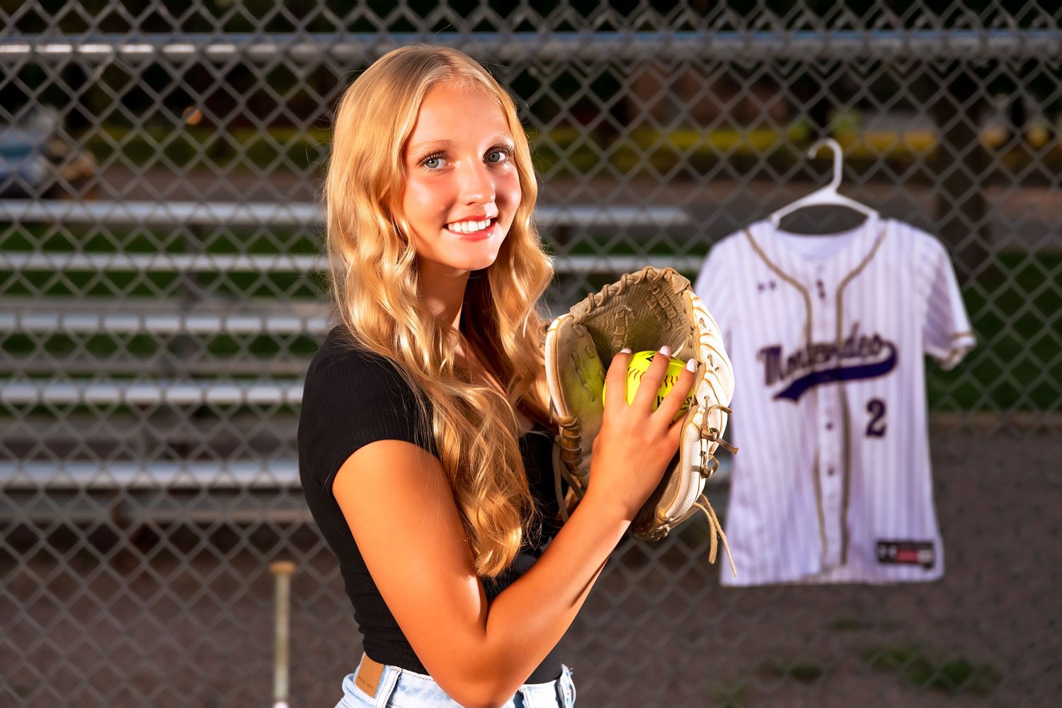 Senior portrait photoshoot at tennis courts with sports equipment and jersey.