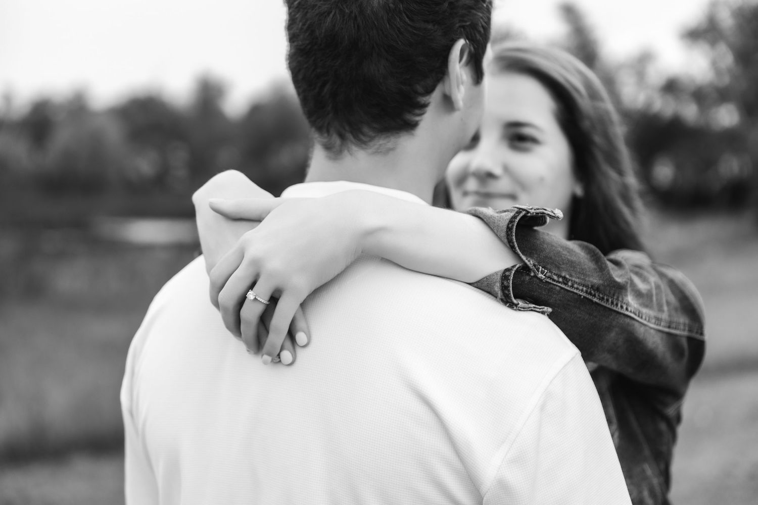Two people embracing in a tender moment outdoors against a soft blurred background.