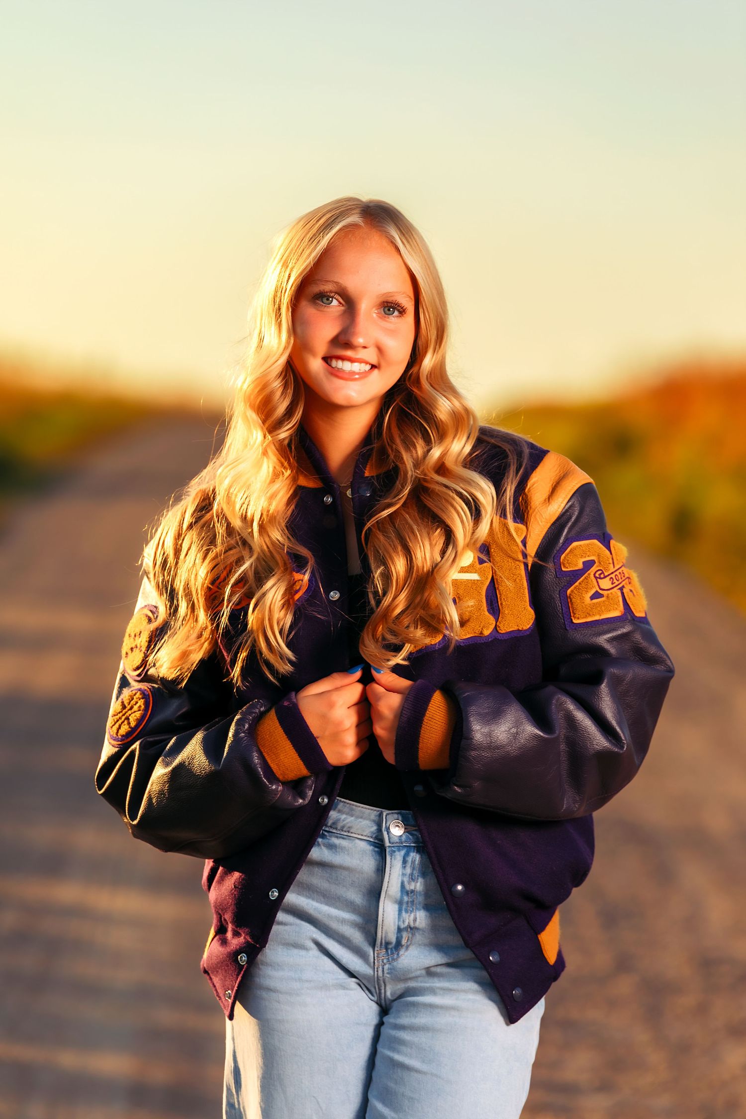Casual sports photoshoot featuring varsity jacket and denim against sunset backdrop.