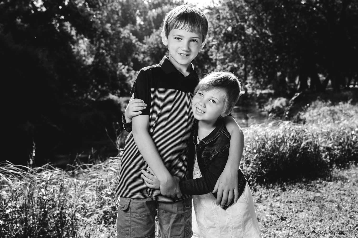 A series of black and white photographs showing a couple sitting and embracing in a sun-dappled outdoor setting.